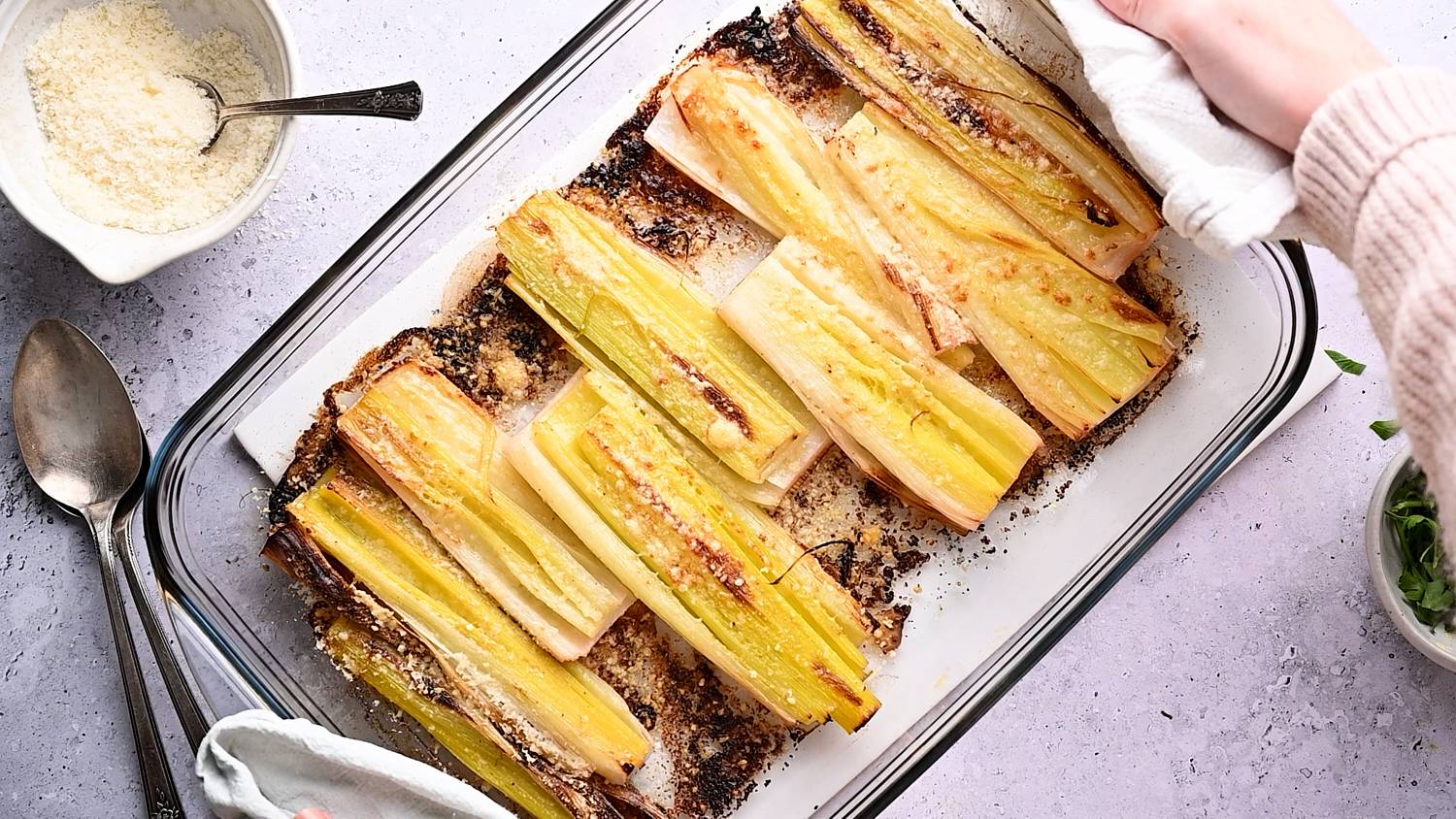 Roasted Parmesan leeks in a baking dish with crispy, golden brown edges.