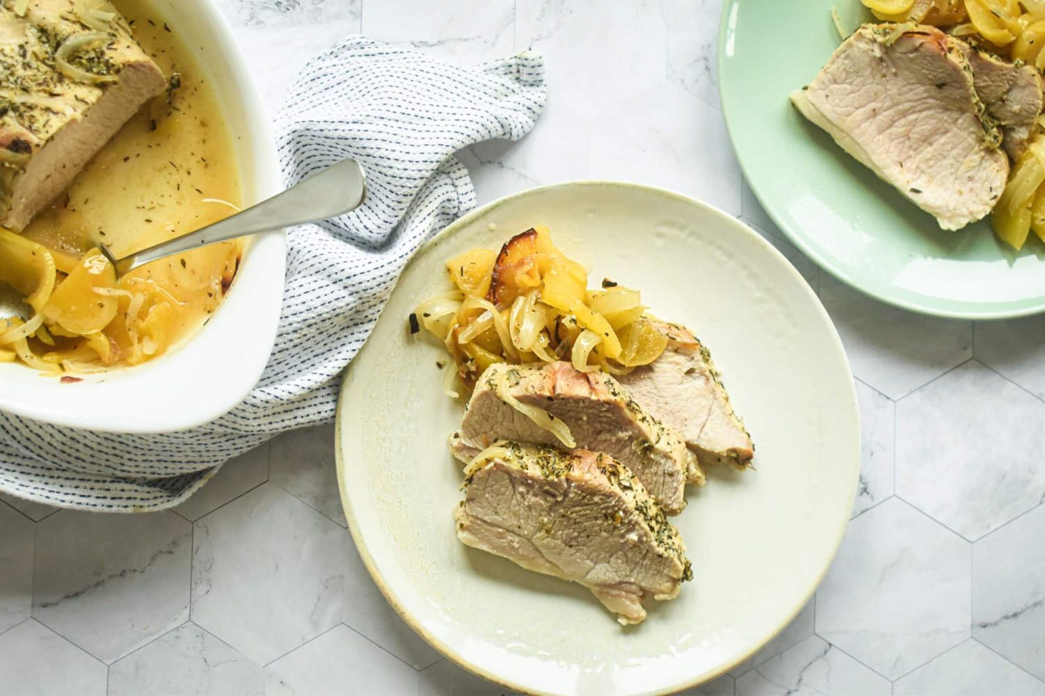 Pork and apples roasted with onions and herbs slice don a plate and served in a casserole dish.