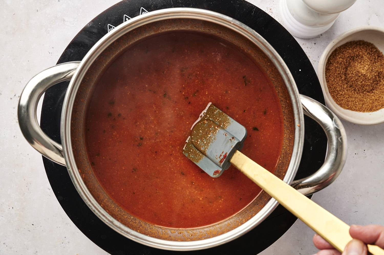 Place red enchilada sauce in pan and add spices.