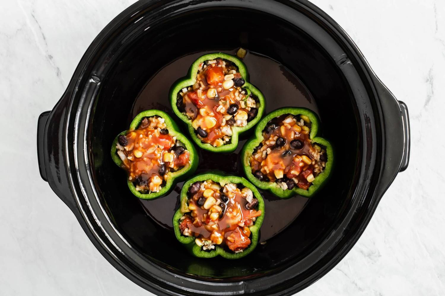 Slow cooker with vegetarian stuffed bell peppers drizzled with barbecue sauce.