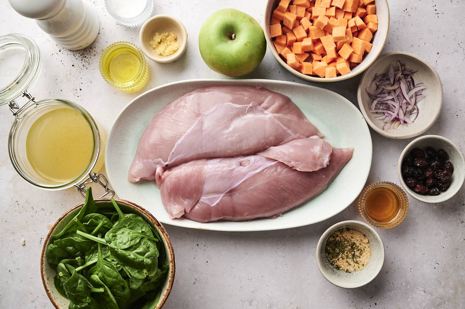 Ingredients for stuffed turkey including turkey breast, sweet potatoes, shallots, dried cranberries, spinach, and spices.