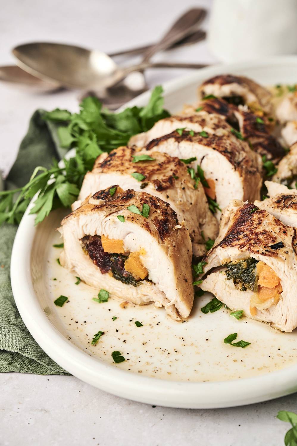 Sliced turkey tenderloin stuffed with apples, cranberries, spinach, and sweet potatoes on a plate. 