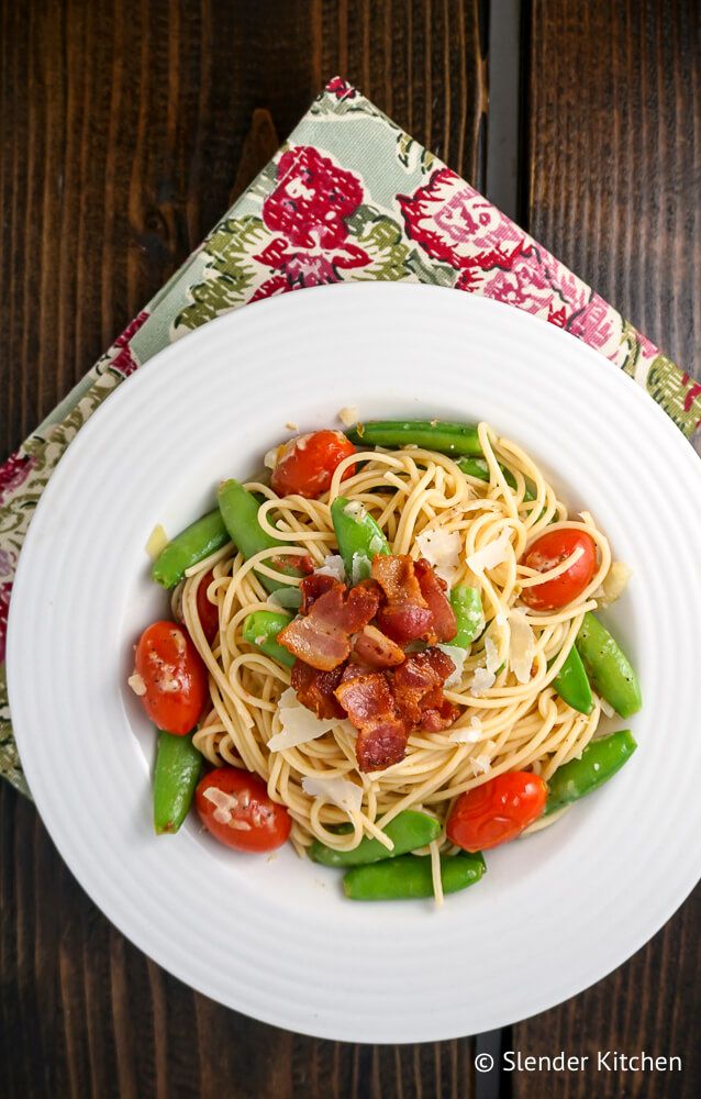 Sugar Snap Pea Pasta with bacon, Parmesan cheese, and cherry tomatoes in a bowl with a flowered napkin.