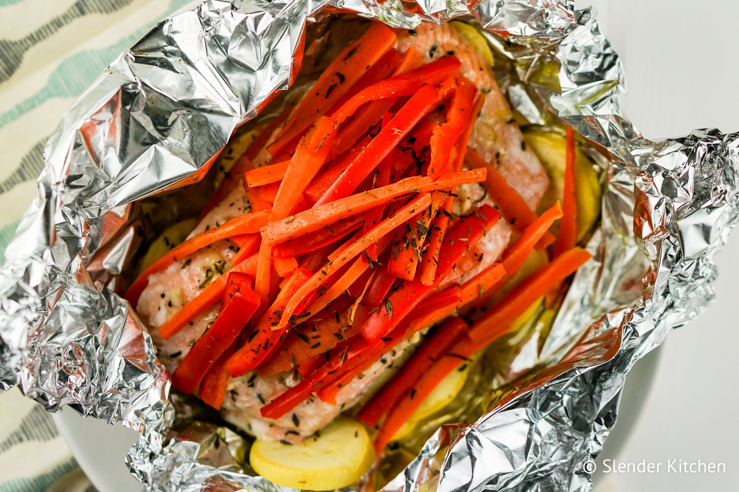 Honey glazed salmon in a foil packet and topped with carrots and peppers.