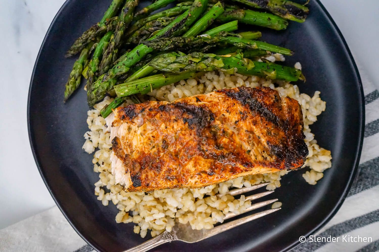 Cajun salmon coated with spice rub and served on a plate with vegetables.