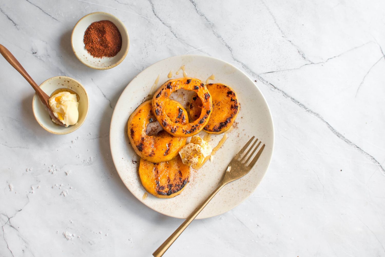 Grilled butternut squash on a plate with butter and cinnamon.