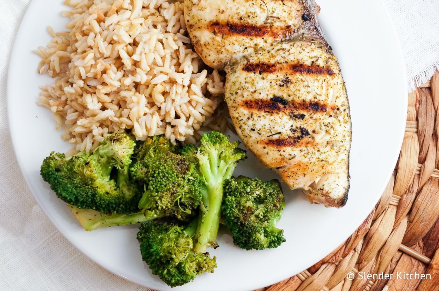 Grilled lemon pepper mahi mahi on a plate with rice and broccoli.