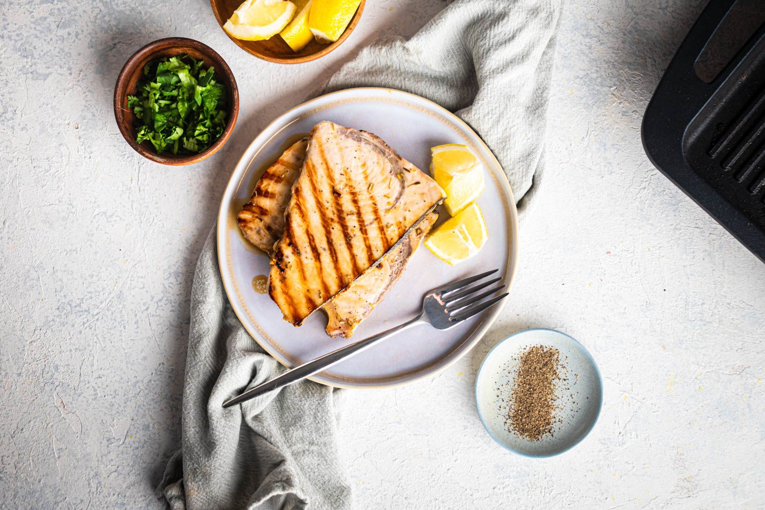 Grilled swordfish on a plate with lemon and parsley.