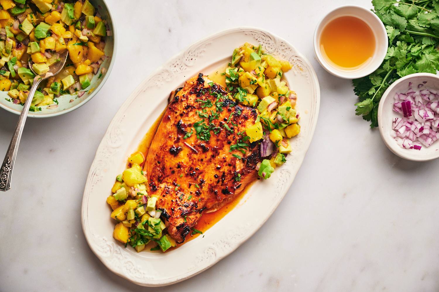 Honey chipotle salmon served with mango salsa on a large white plate.