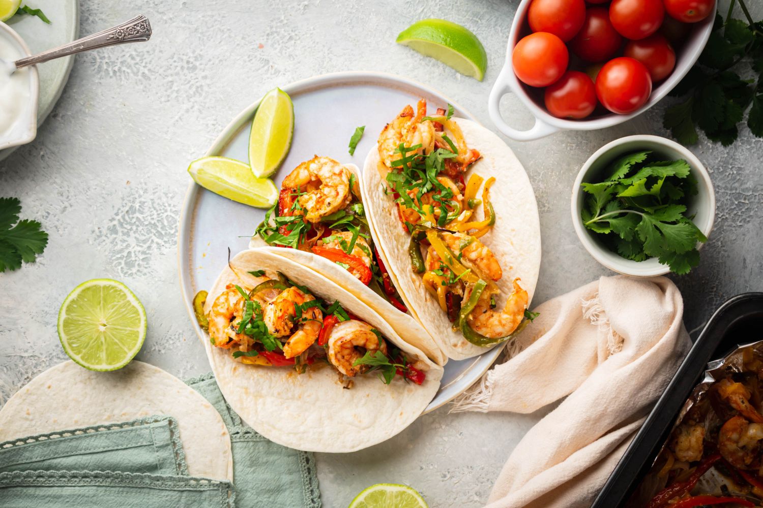 Shrimp fajitas with peppers and onions on corn tortillas with salsa and lime.