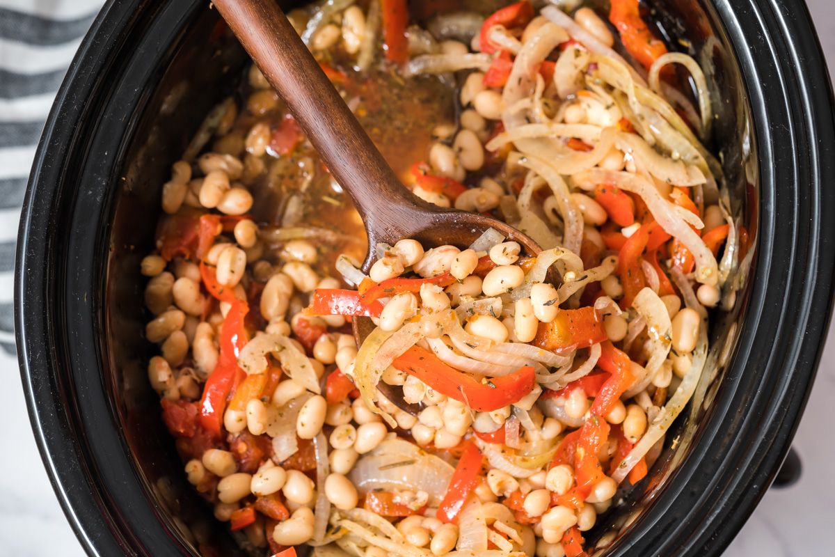 Crockpot Italian red pepper white beans with sliced bell peppers and spices in a slow cooker.