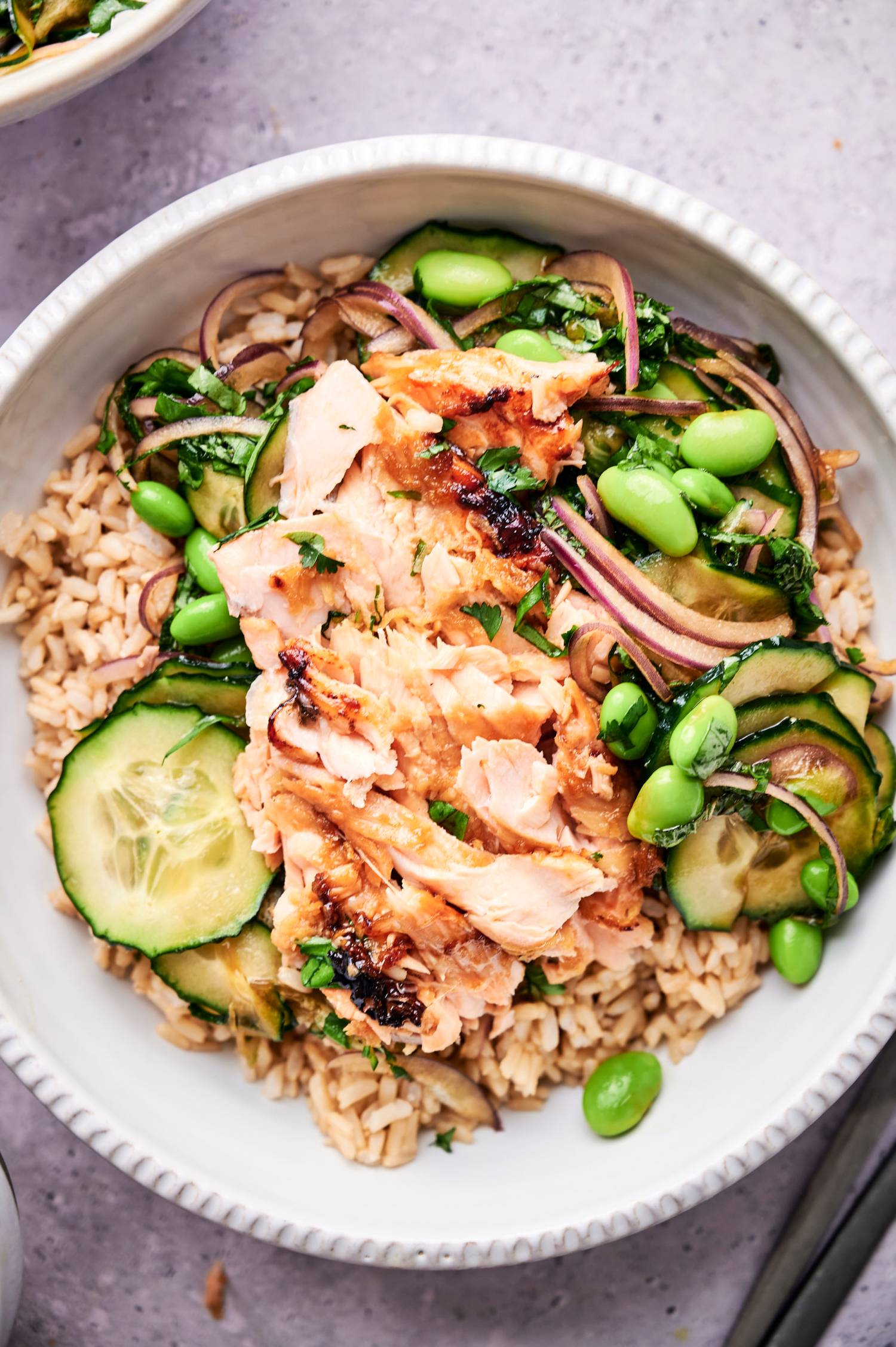 Salmon, vegetable, and brown rice bowls with edamame, cucumber, red onion, cilantro, basil, and mint.