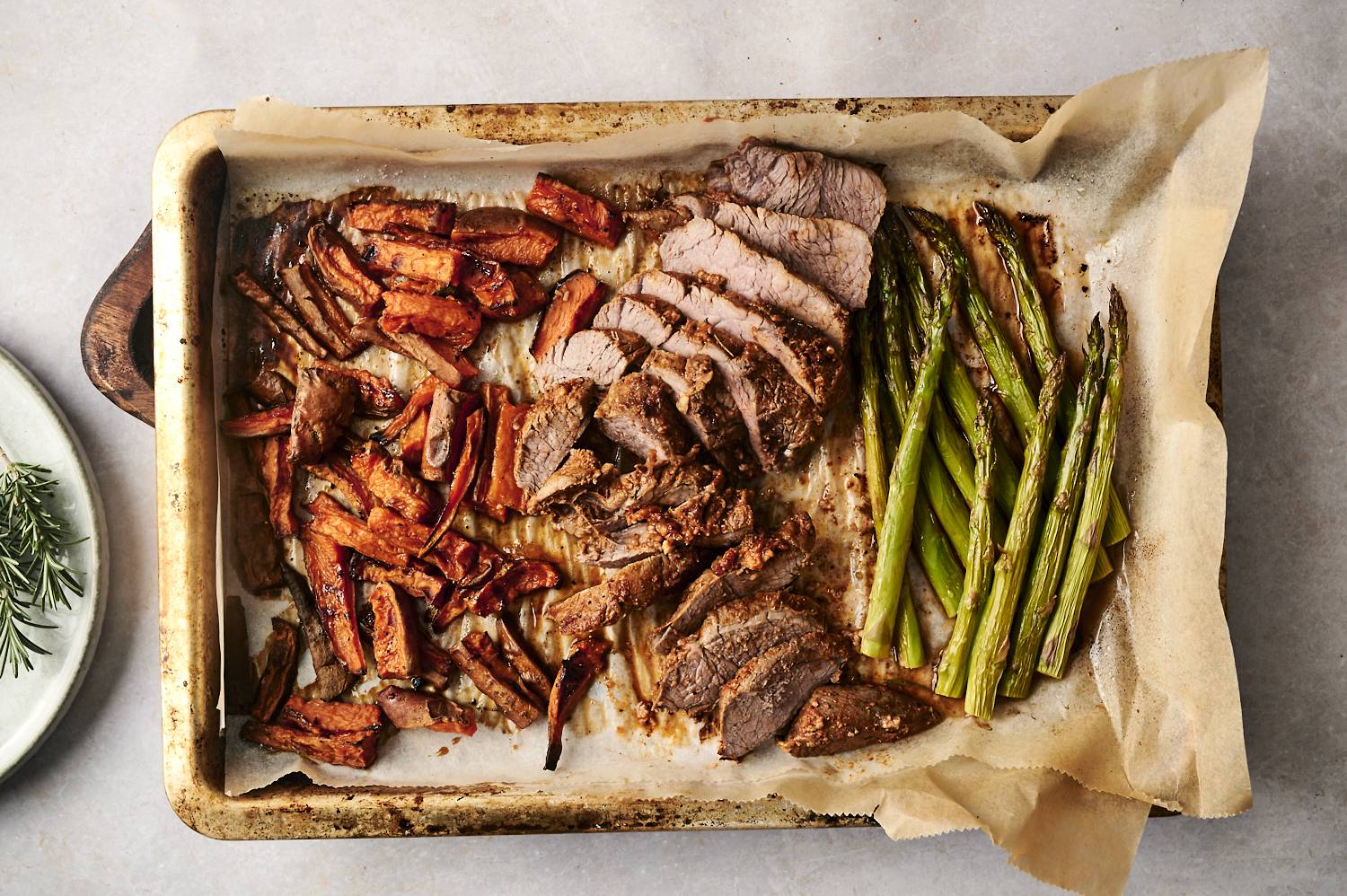 A hearty sheet pan meal featuring perfectly roasted asparagus, sweet potato wedges, and tender slices of rosemary-seasoned steak, all cooked to golden perfection.