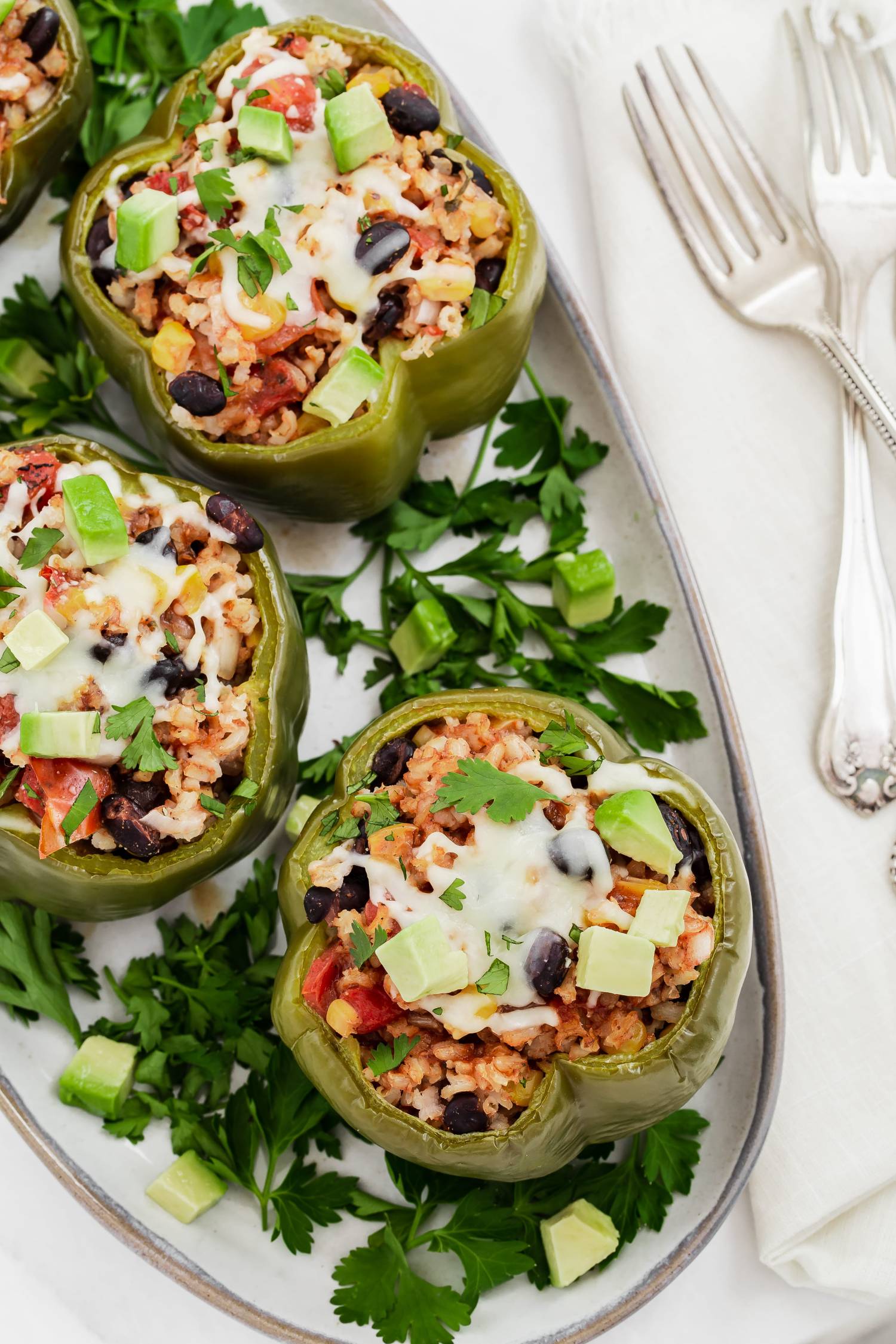 Crockpot vegetarian stuffed bell peppers with corn, black beans, rice, and tomatoes served with barbecue sauce and melted cheese.