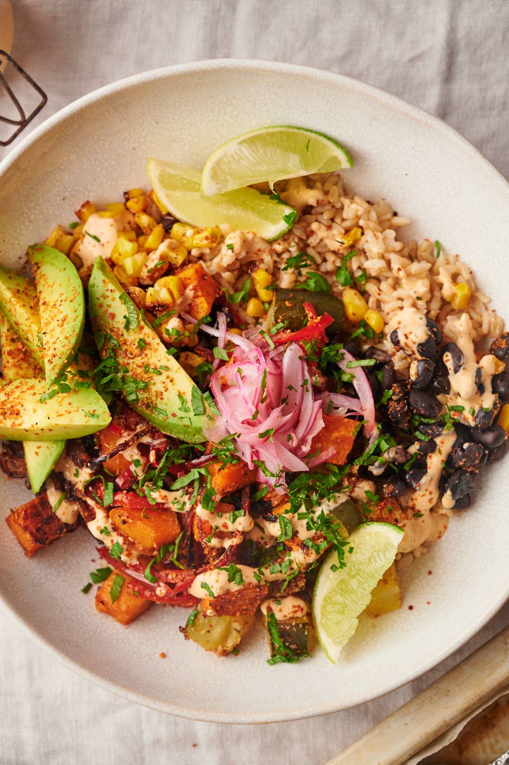 Sweet potato black bean bowls with zucchini, corn, peppers, onions, cilantro, and avocado.