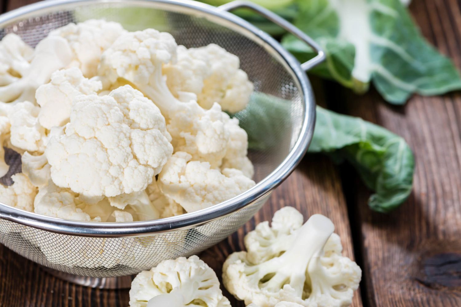 A bowl of cauliflower florets and a cutting board.