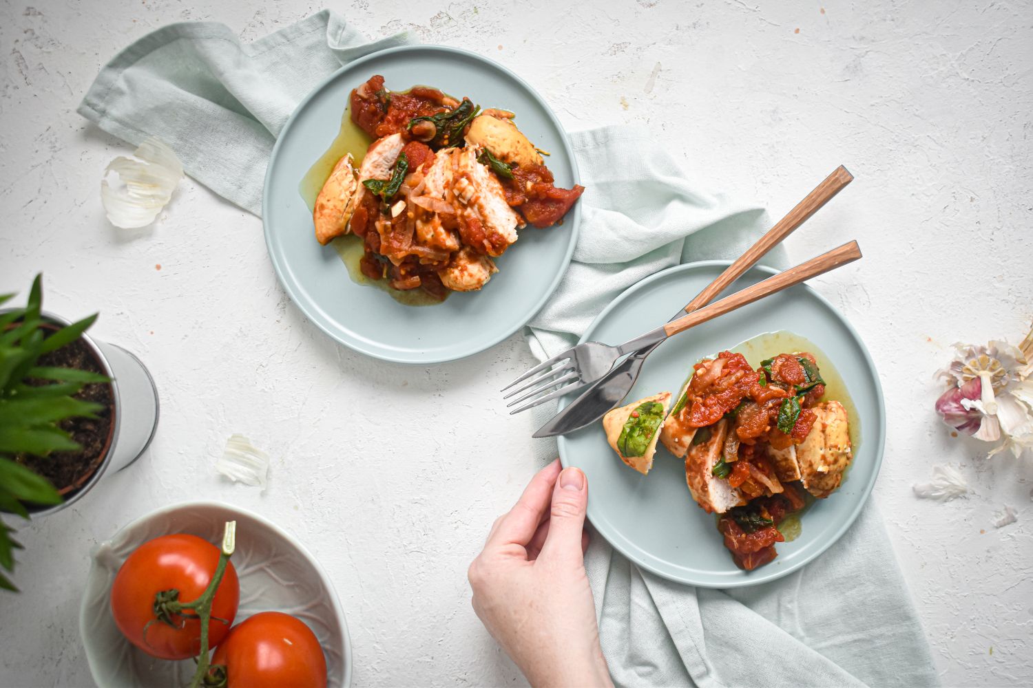 Whole30 slow cooker chicken breast with tomatoes, spinach, and balsamic vinegar on two plates.