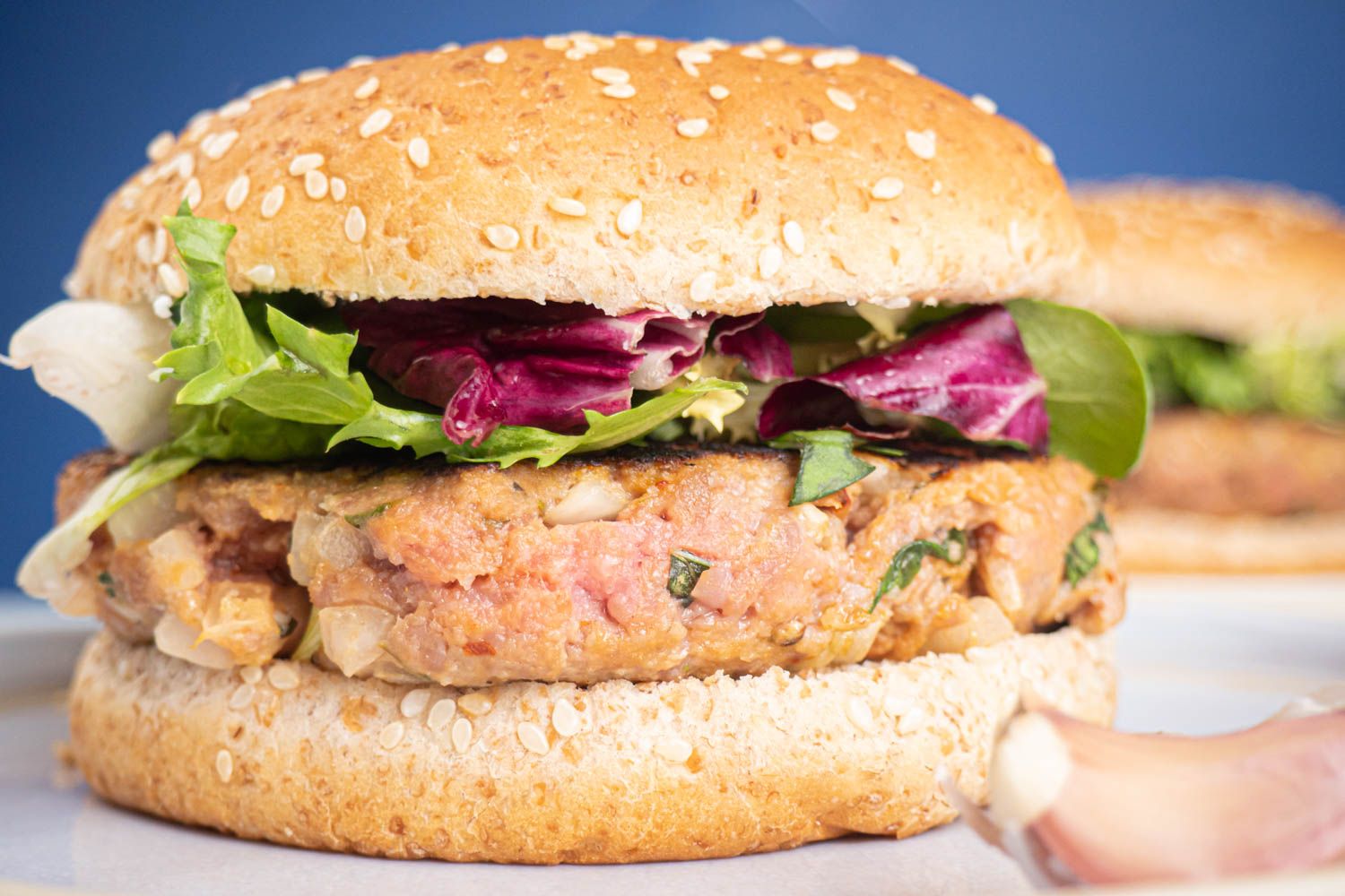 Italian beef burgers on a sesame seed bun with lettuce and tomato.