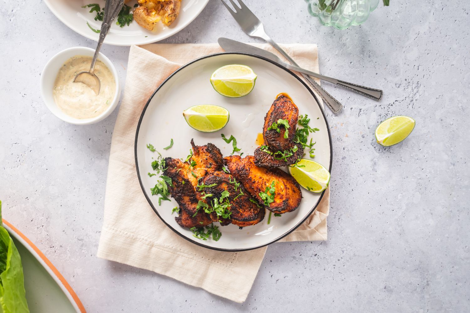 Blackened chicken breast with a crispy exterior on a plate with lime and cilantro.