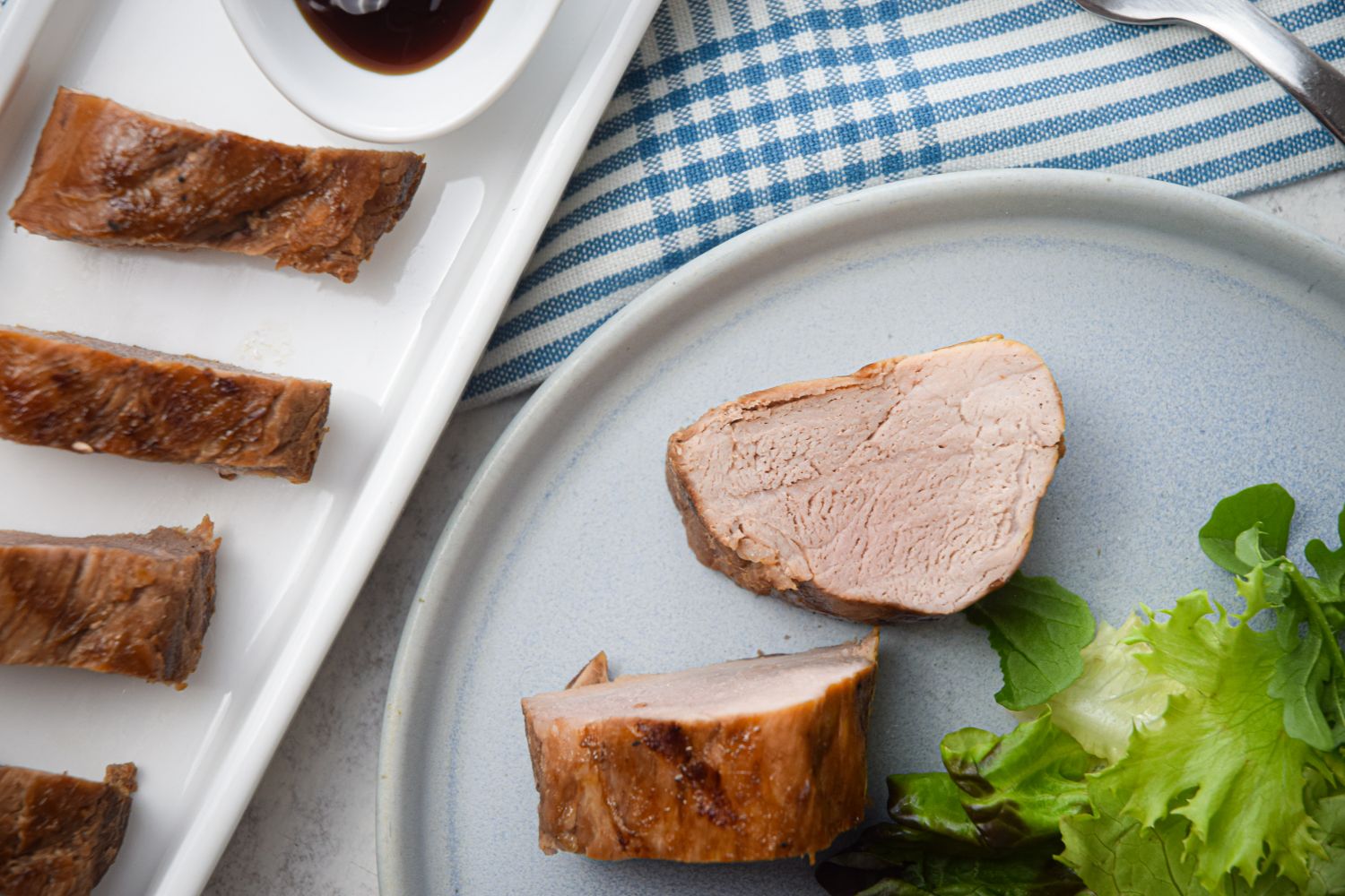 Grilled hoisin pork tenderloin with an Asian marinade on a plate with greens.