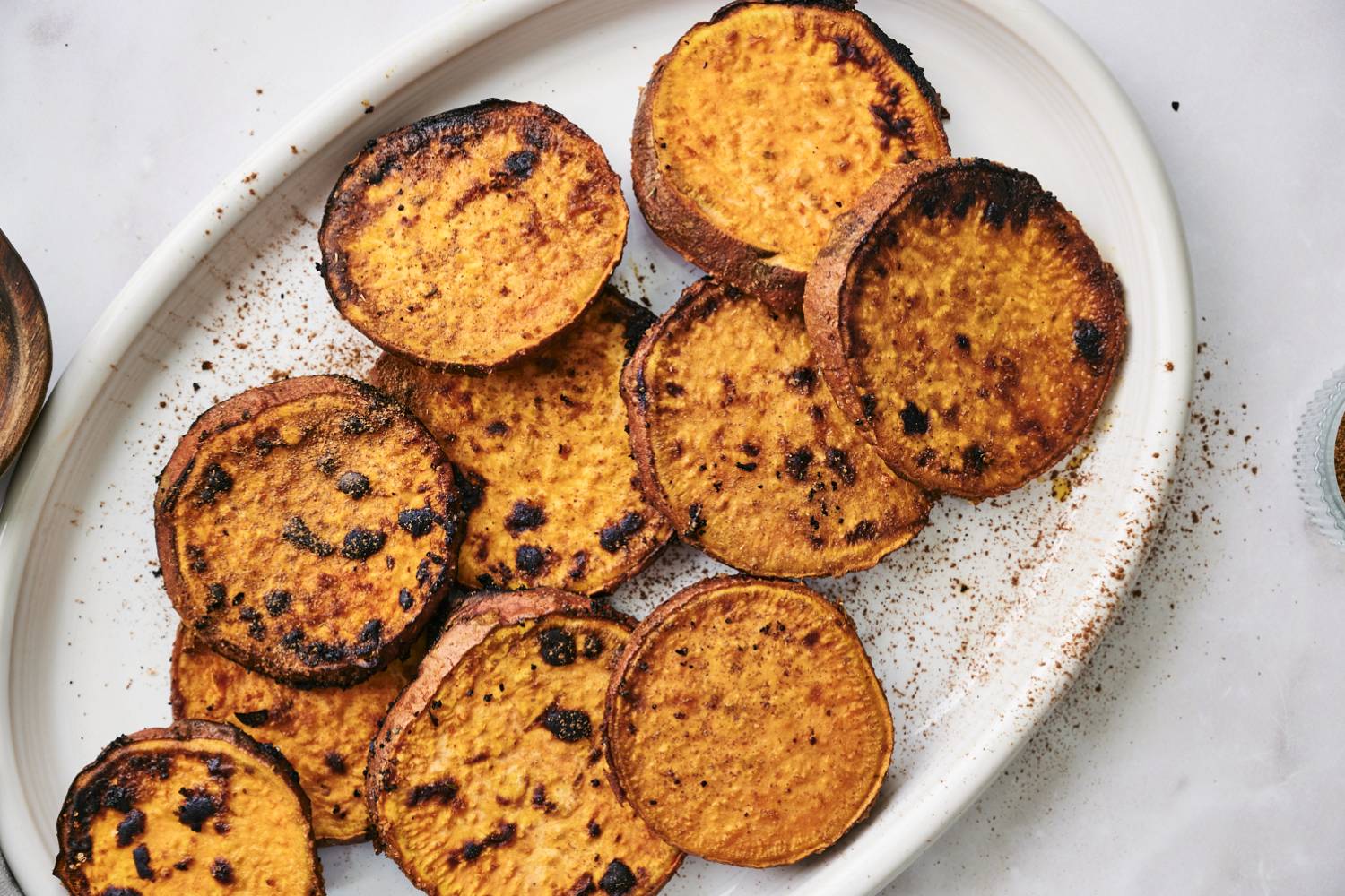 Grilled sweet potatoes with olive oil and spices on a large white plate.