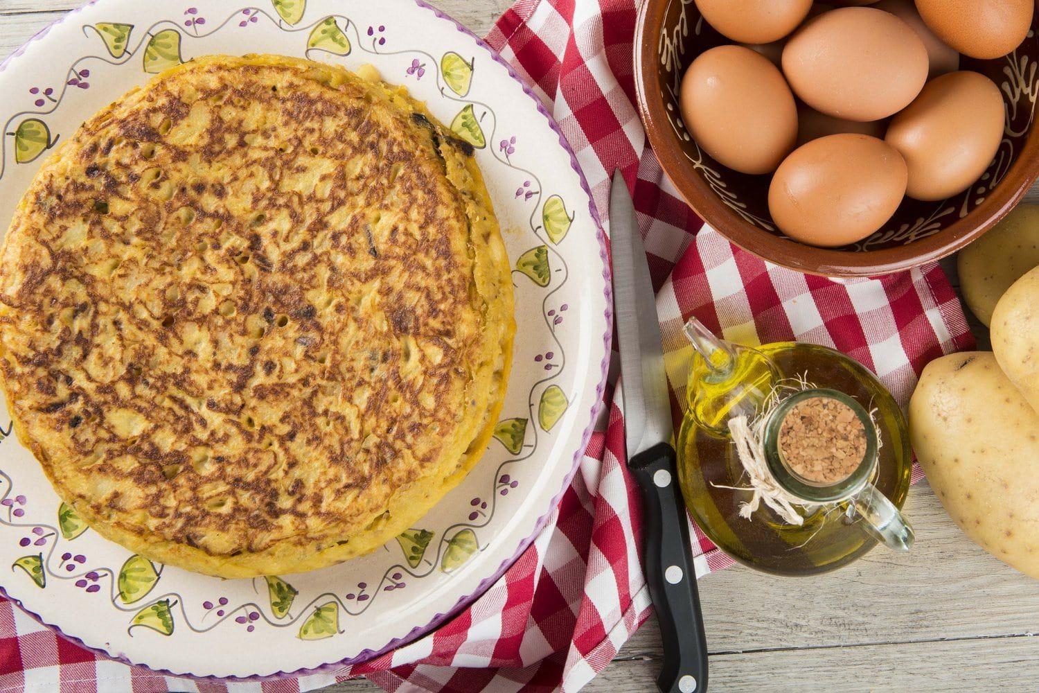 Tortilla espanola with potatoes, eggs, onions, and browned edges served on a plate. 