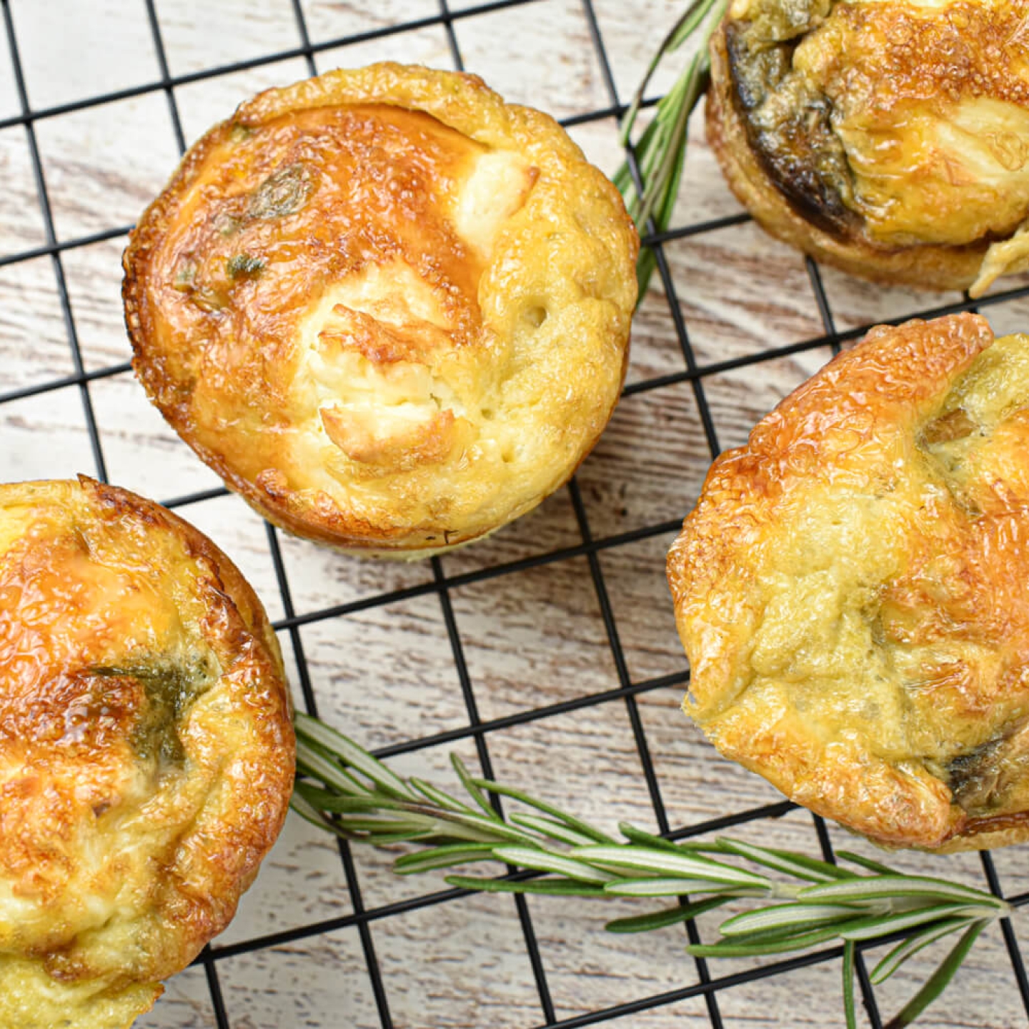 Asparagus frittata with mushrooms and feta cheese on a baking rack with rosemary.