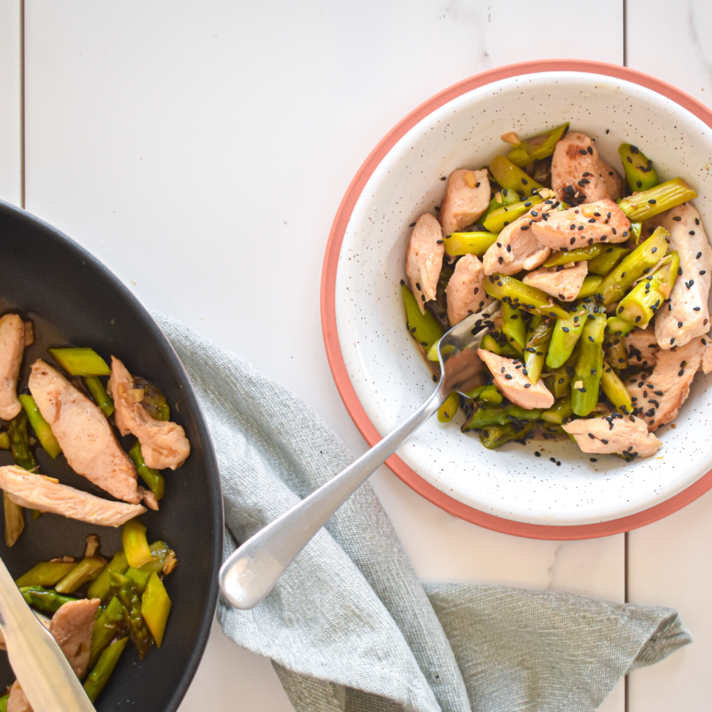 Chicken and asparagus stir fry with thinly sliced chicken breast, chopped asparagus, stir fry sauce, and sesame seeds in a bowl.