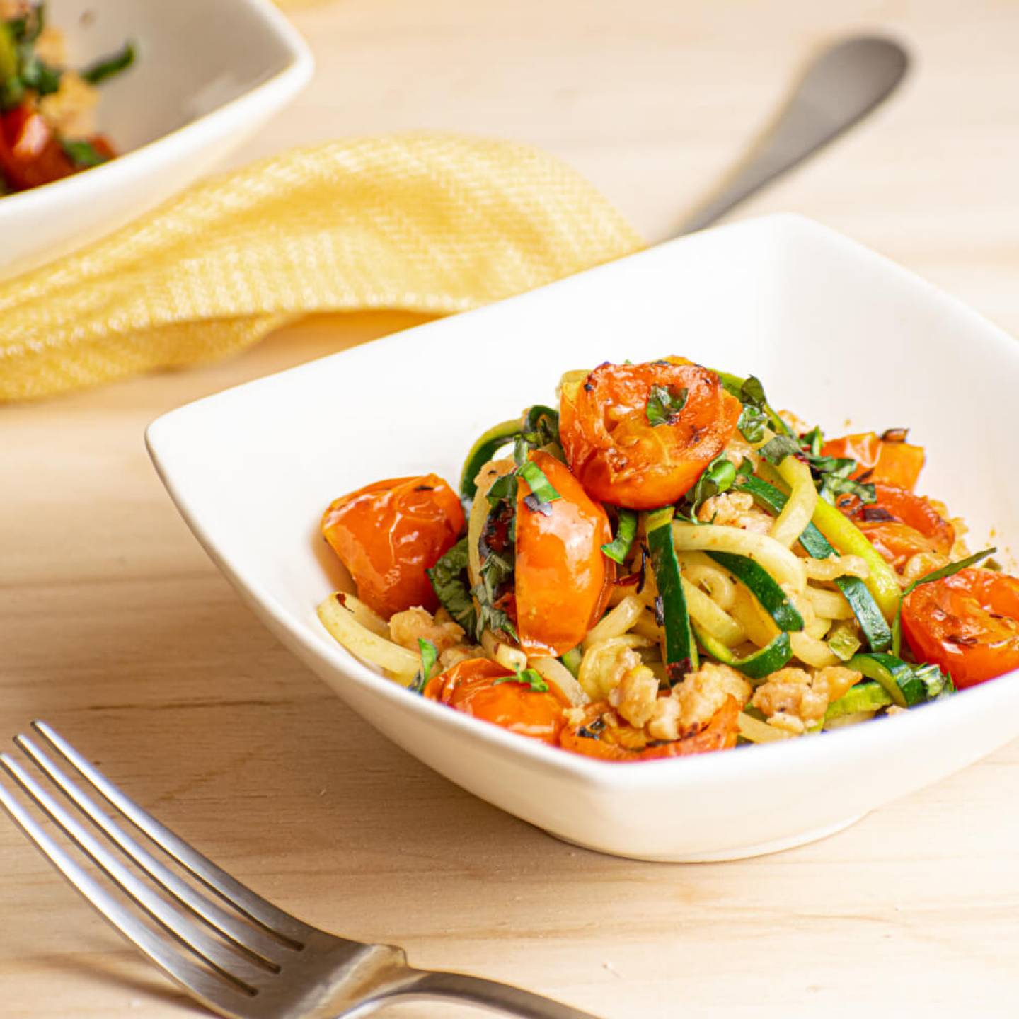 Garlic zucchini noodles with ground sausage and cherry tomatoes in a bowl.