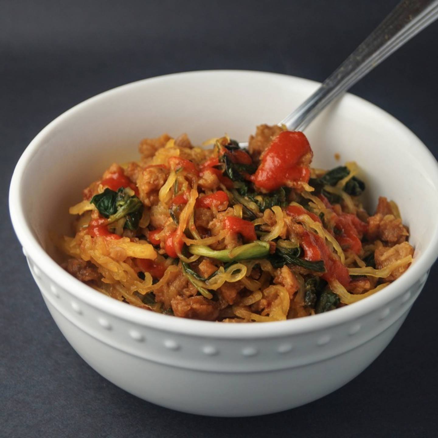 Asian spaghetti squash with crumbled sausage, spinach, spicy sauce, and cooked spaghetti squash noodles.