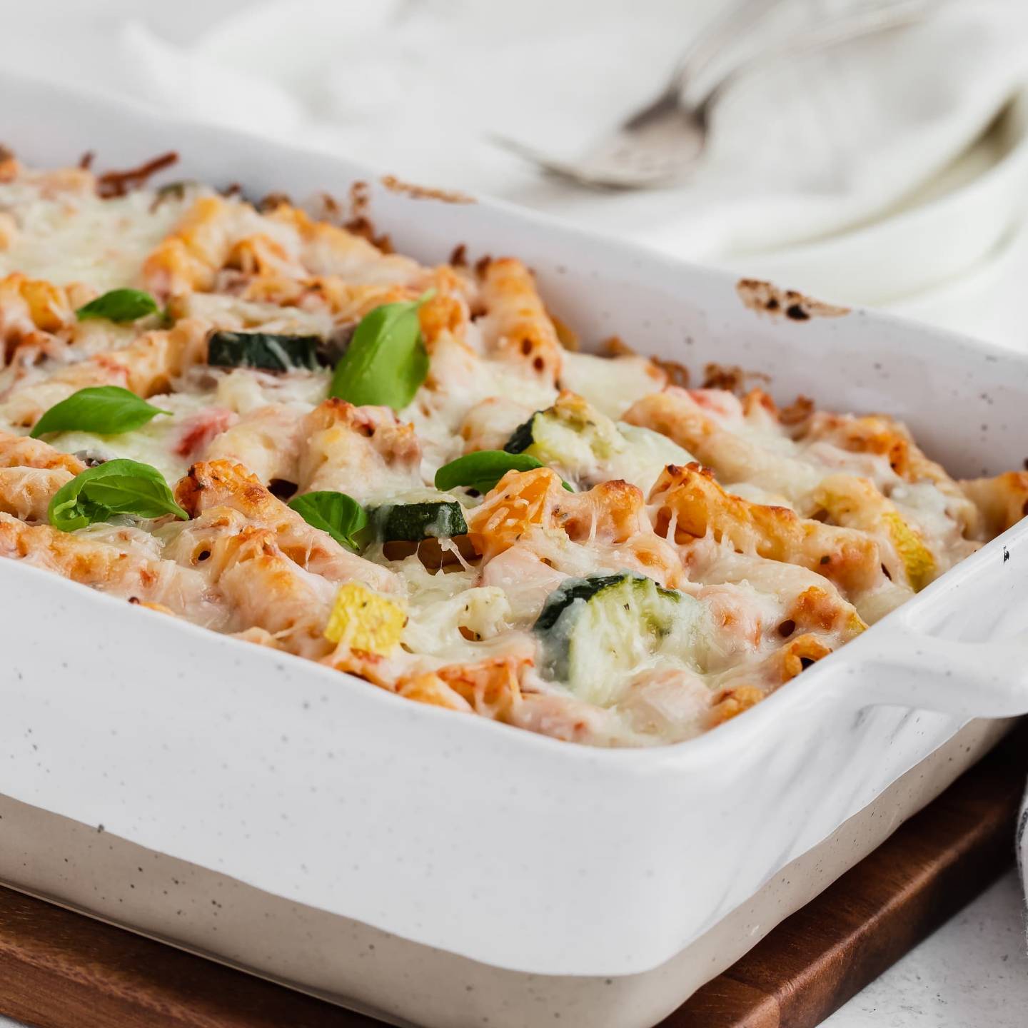 Roasted Vegetable Baked Ziti with melted cheese in a white casserole dish.