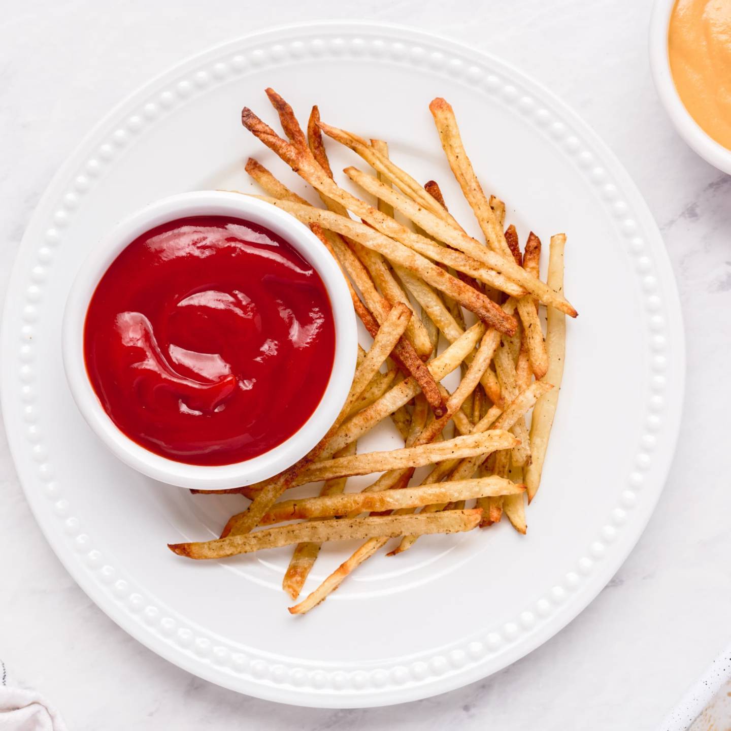 Baked skinny fries with crispy baked potatoes and turnips on a plate with ketchup.