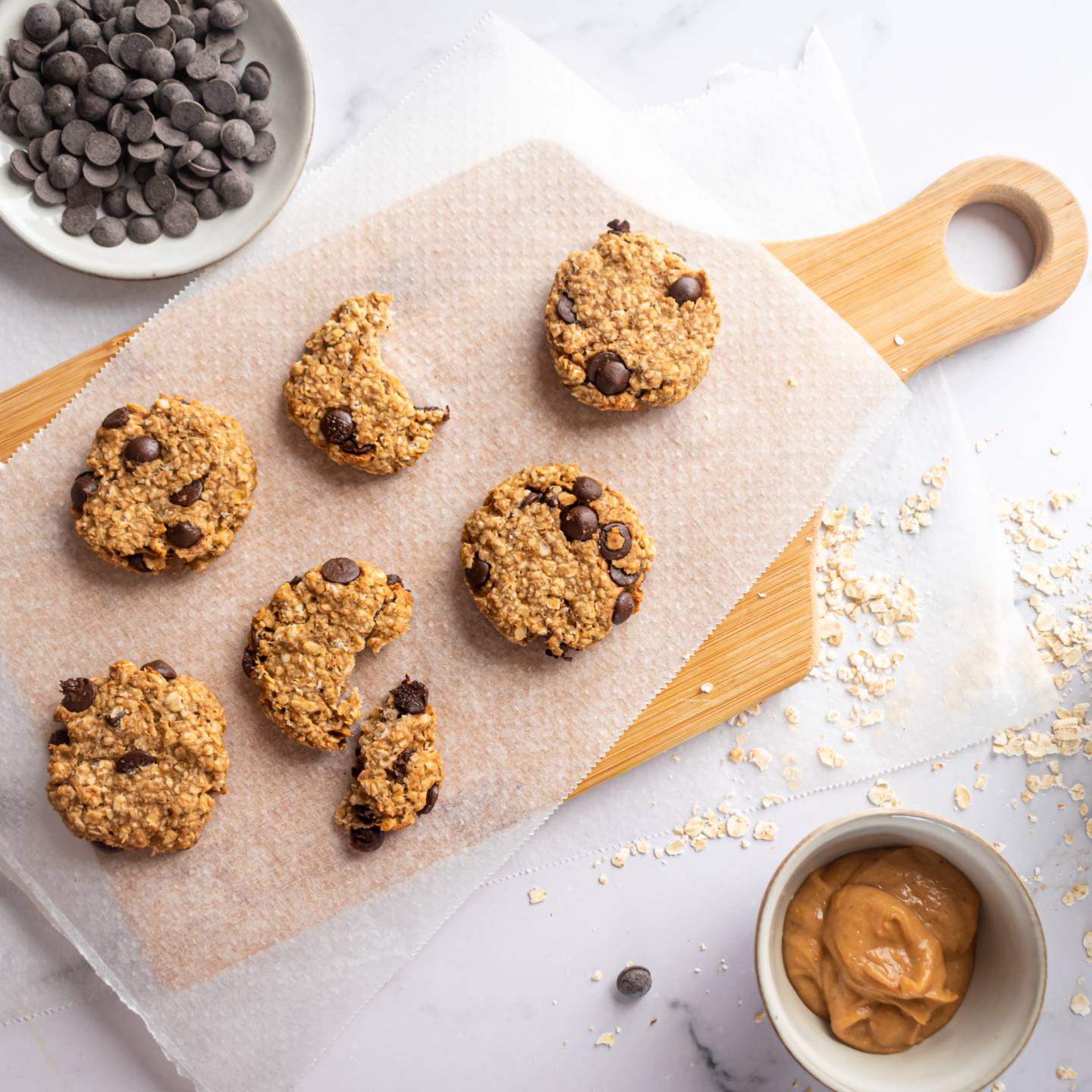 Banana oatmeal cookies with chocolate chips on a wooden cutting board.