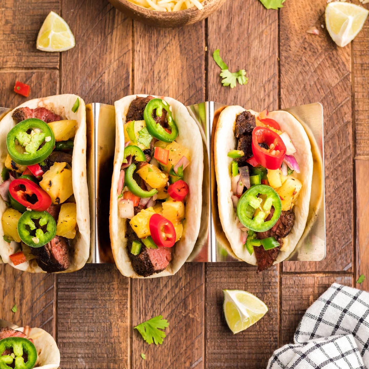 Blackened steak tacos with seared steak served on flour tortillas with pineapple salsa, cilantro, and jalapenos.