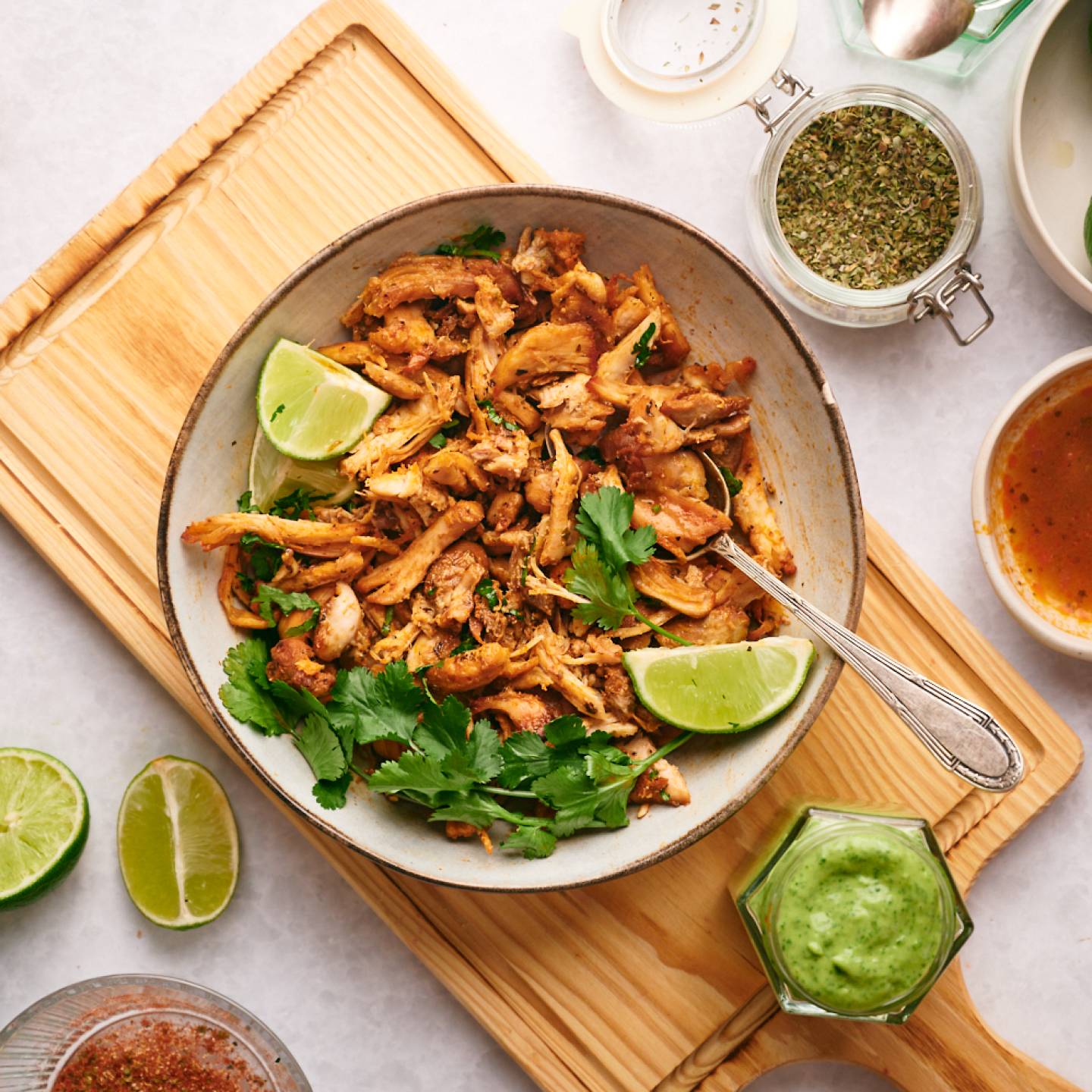 Chicken carnitas made with crispy chicken thighs, spices, and lime juice in a bowl with salsa on the side. 