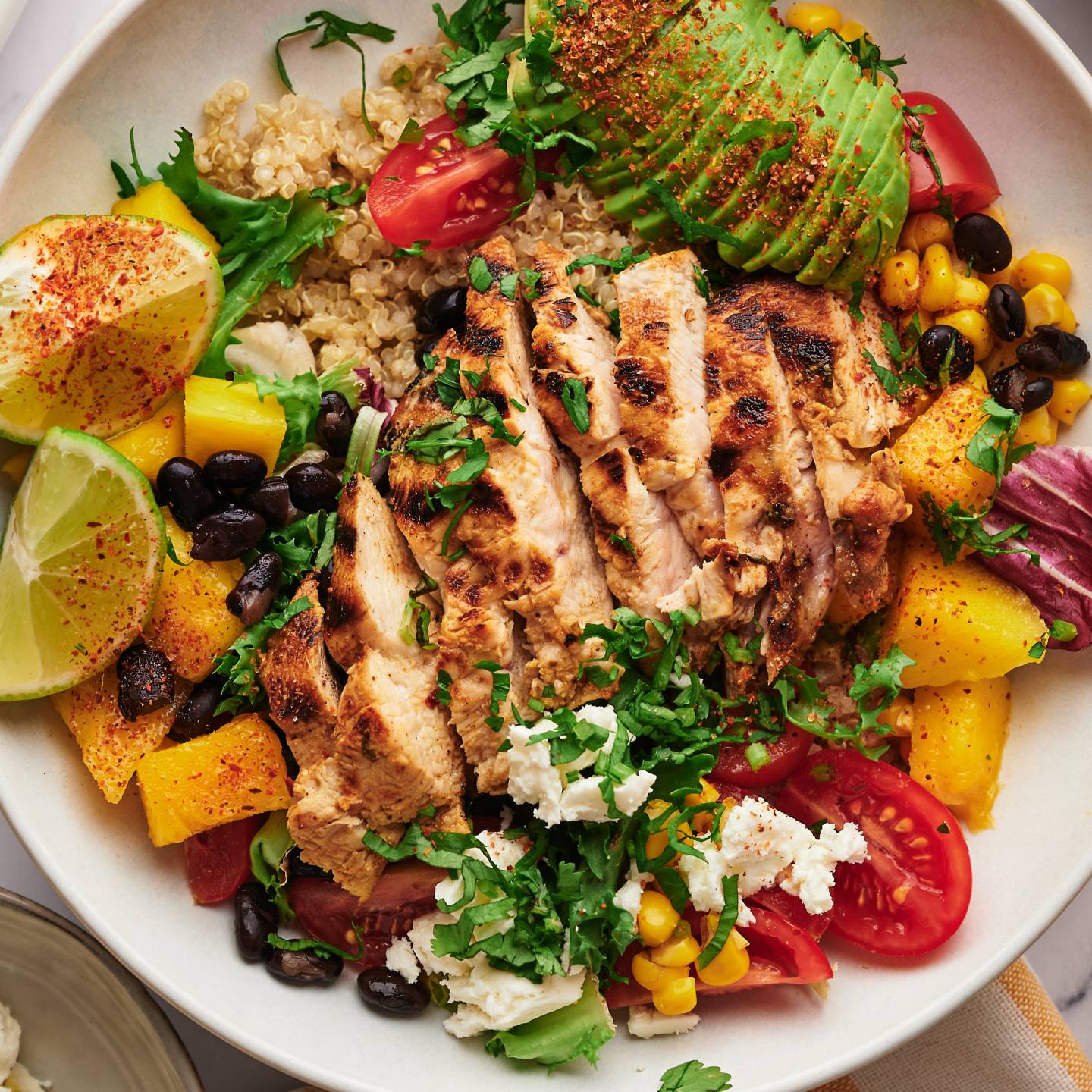 Chicken quinoa bowls with sliced grilled chicken, pico de gallo, cilantro, lime, and chili lime dressing.