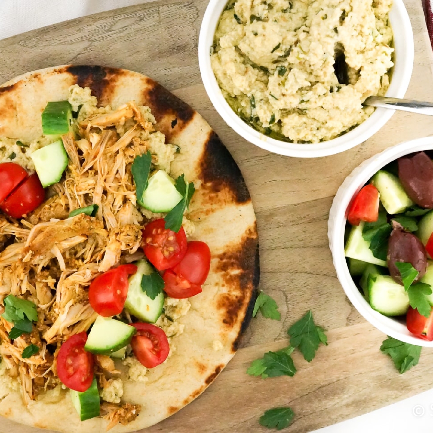 Chicken shawarma on a pita with Israeli salad and hummus on the side.