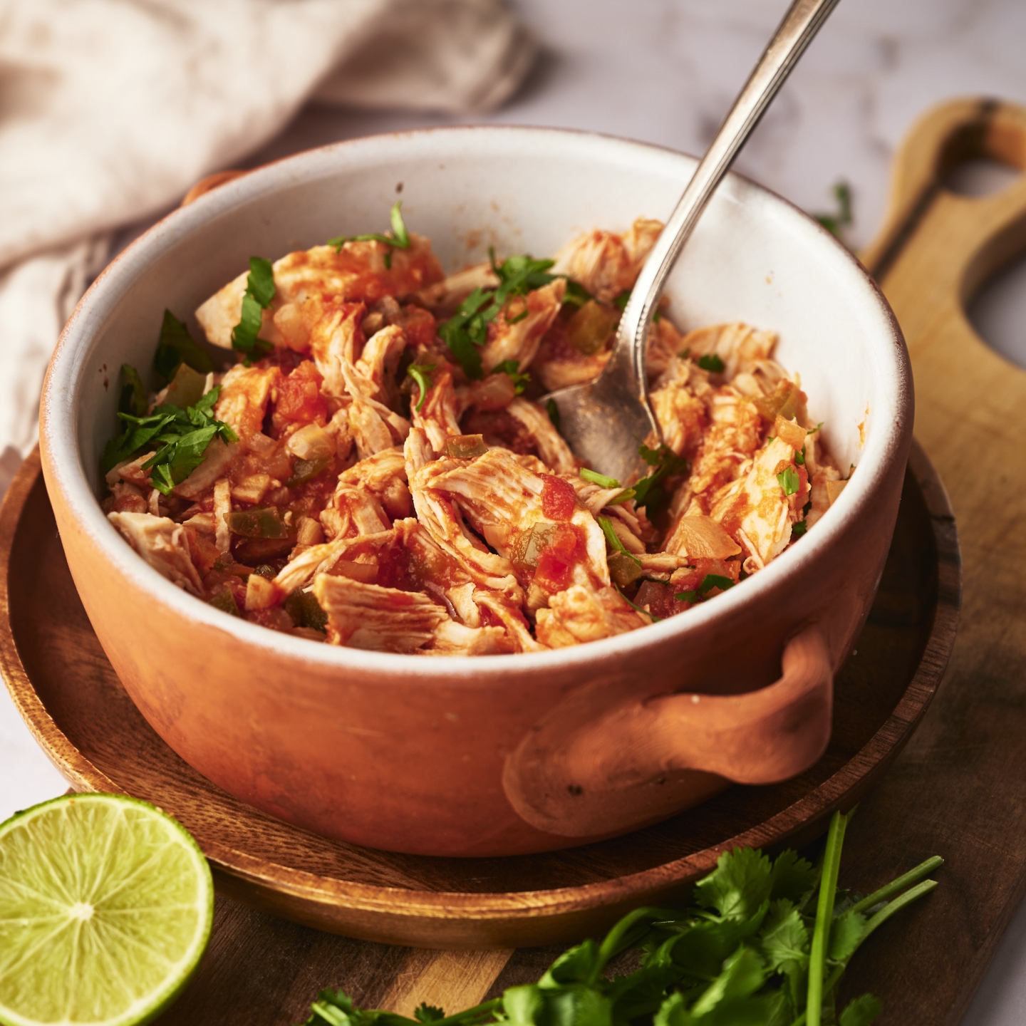 Chicken tinga in a bowl with onions, cilantro, avocado, and queso fresco.