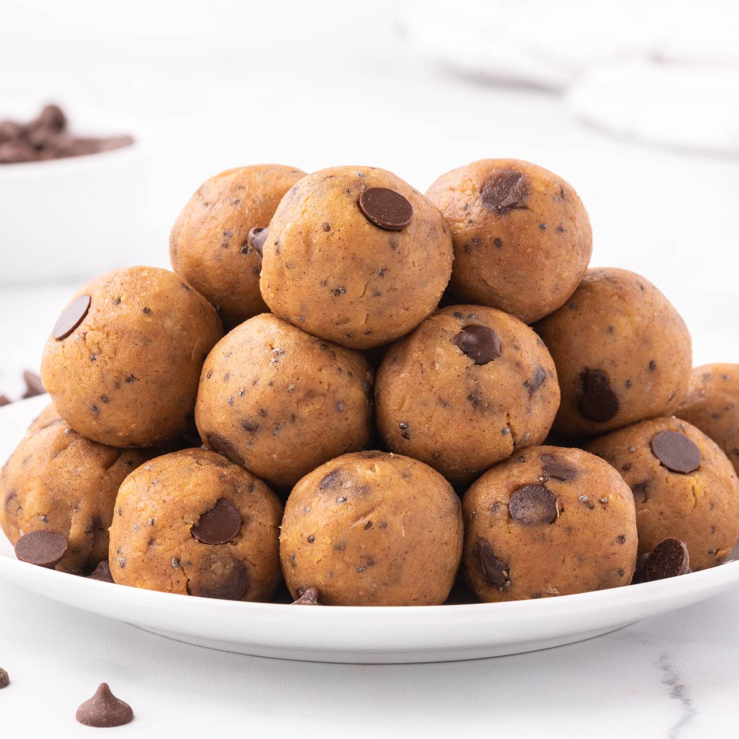 Chickpea cookie dough bites with canned chickpeas, peanut butter, maple syrup, chia seeds, and chocolate chips stacked on a plate.