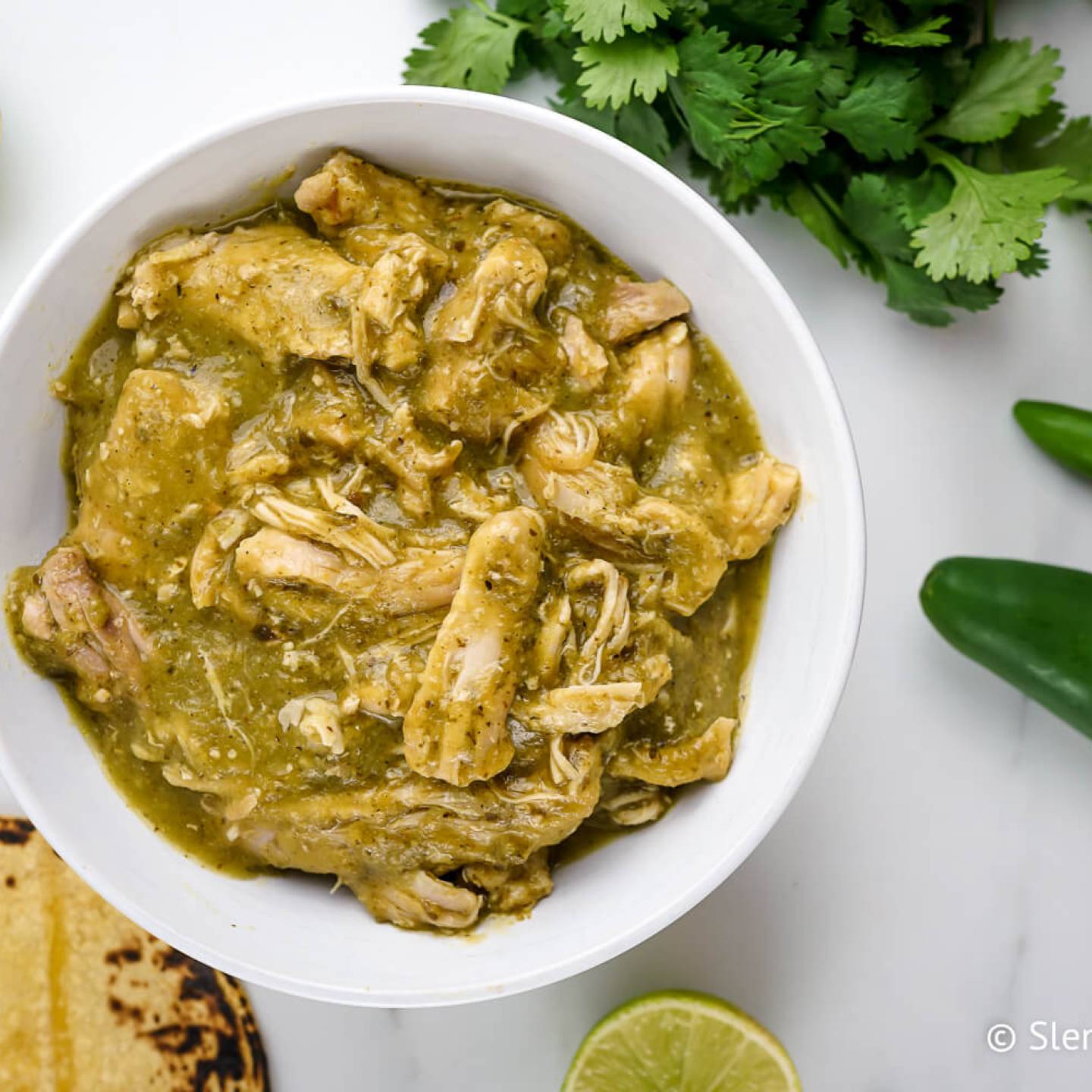 Authentic chile verde made with chicken in a green salsa in a bowl with cilantro.