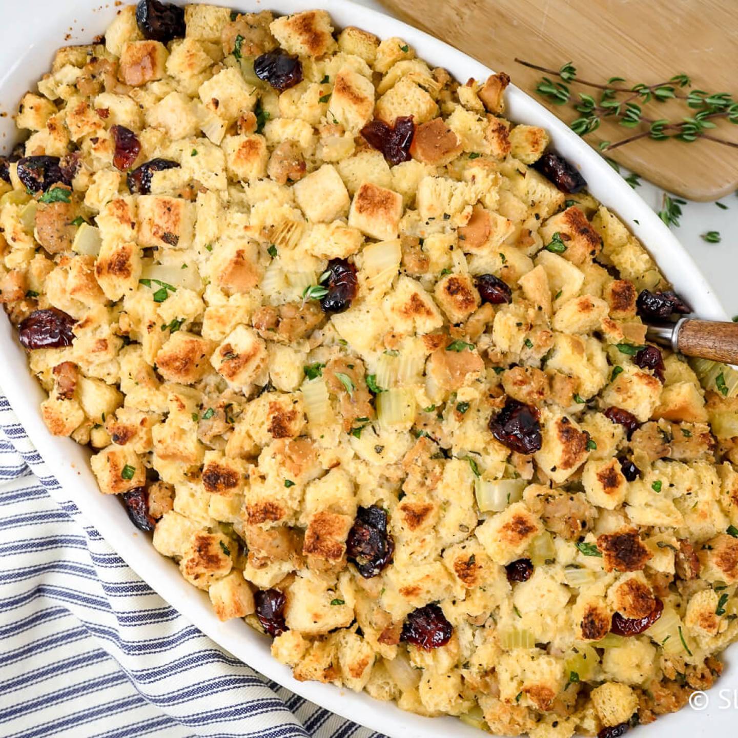 Healthy cornbread sausage stuffing with dried cranberries and thyme in a baking dish.