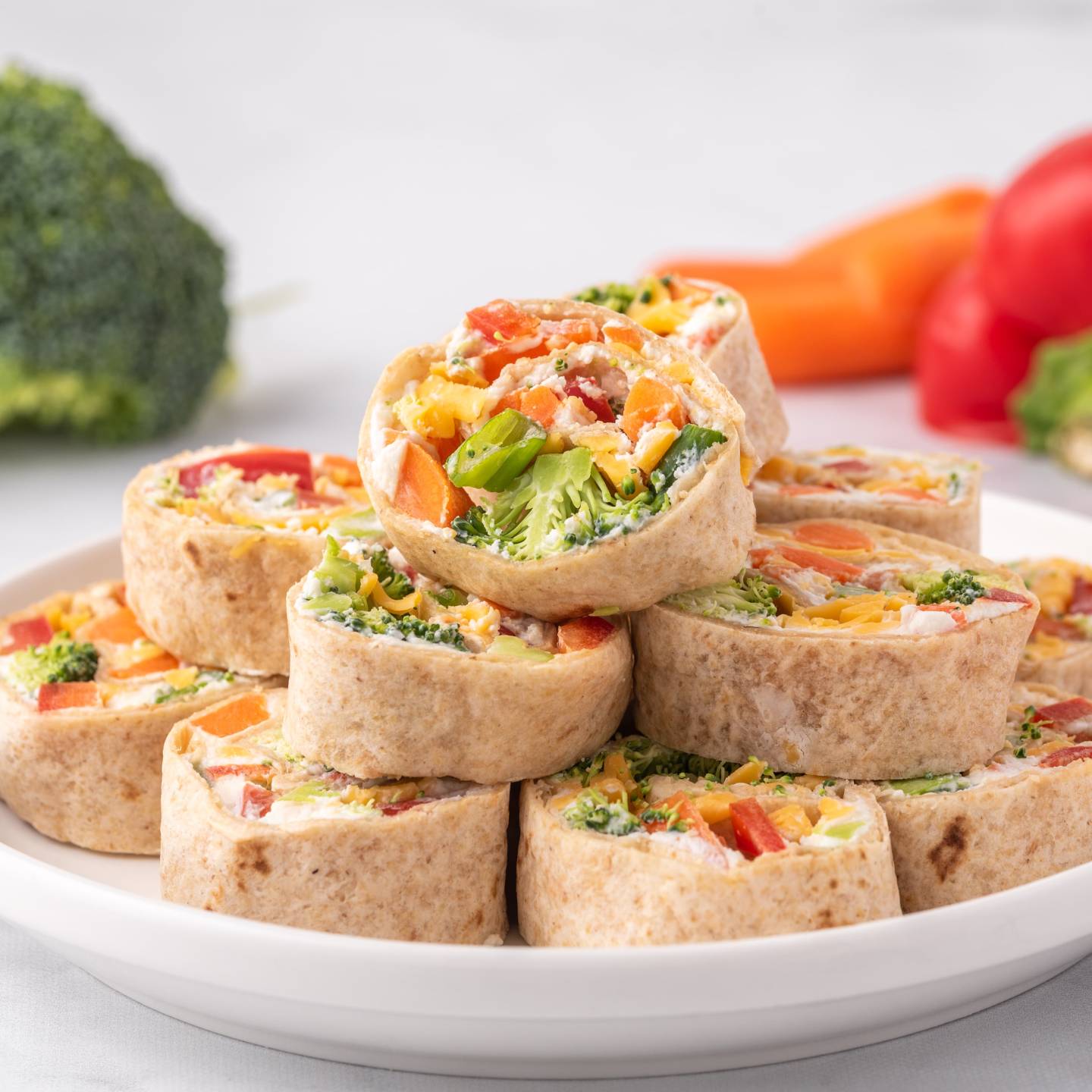 Cream cheese pinwheel with chopped vegetables and ranch seasoning cut into slices on a plate.