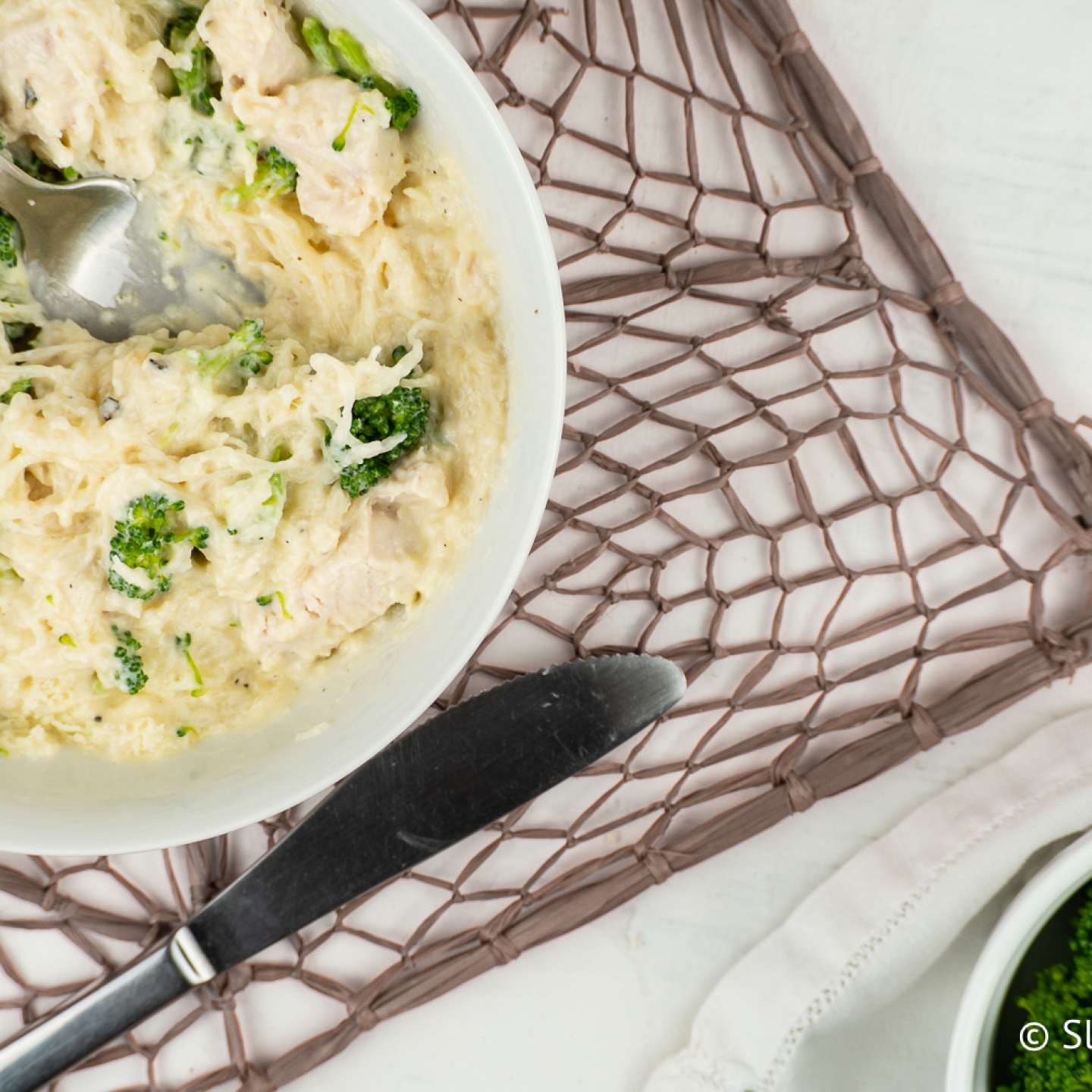 Creamy Parmesan Spaghetti Squash with chicken breast and broccoli in a bowl.