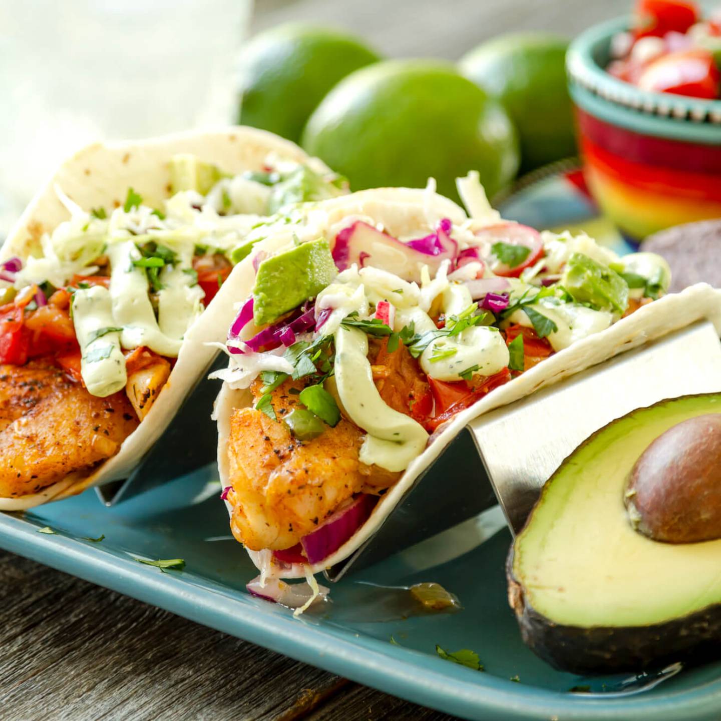  Easy fish tacos with avocado cream on two corn tortillas with a fork and green napkin.