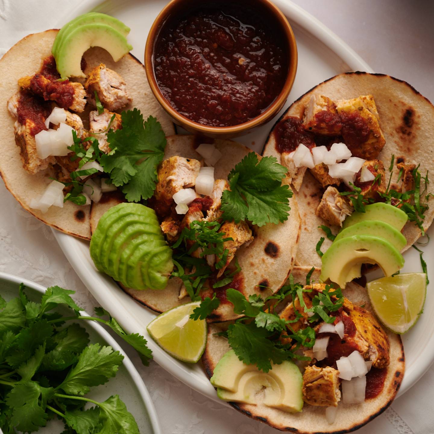 Grilled chicken tacos in a corn tortilla with cilantro and onion on top.