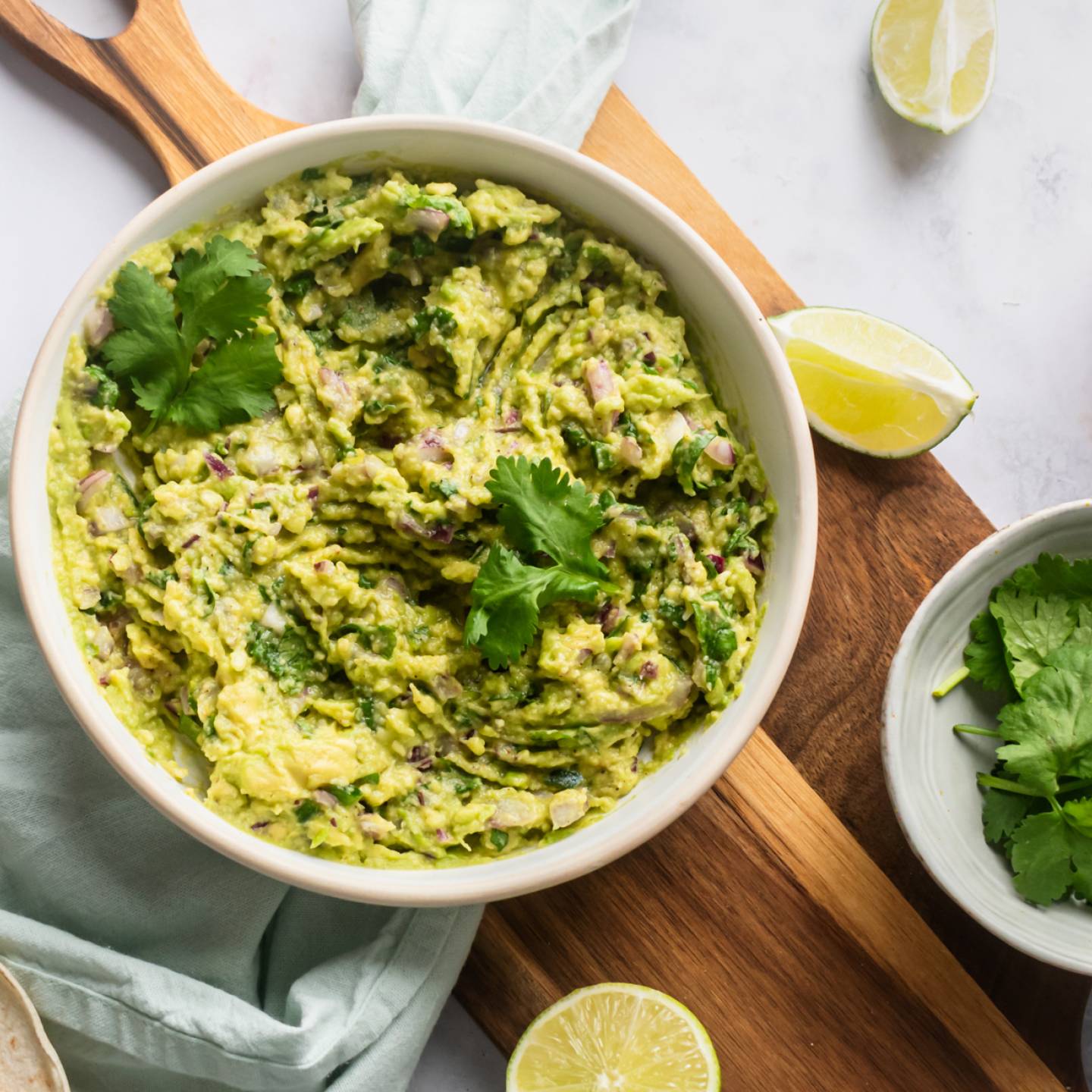 Guacamole with mashed avocados, cilantro, red onion, jalapeno, lime juice, salt, and pepper in a bowl.