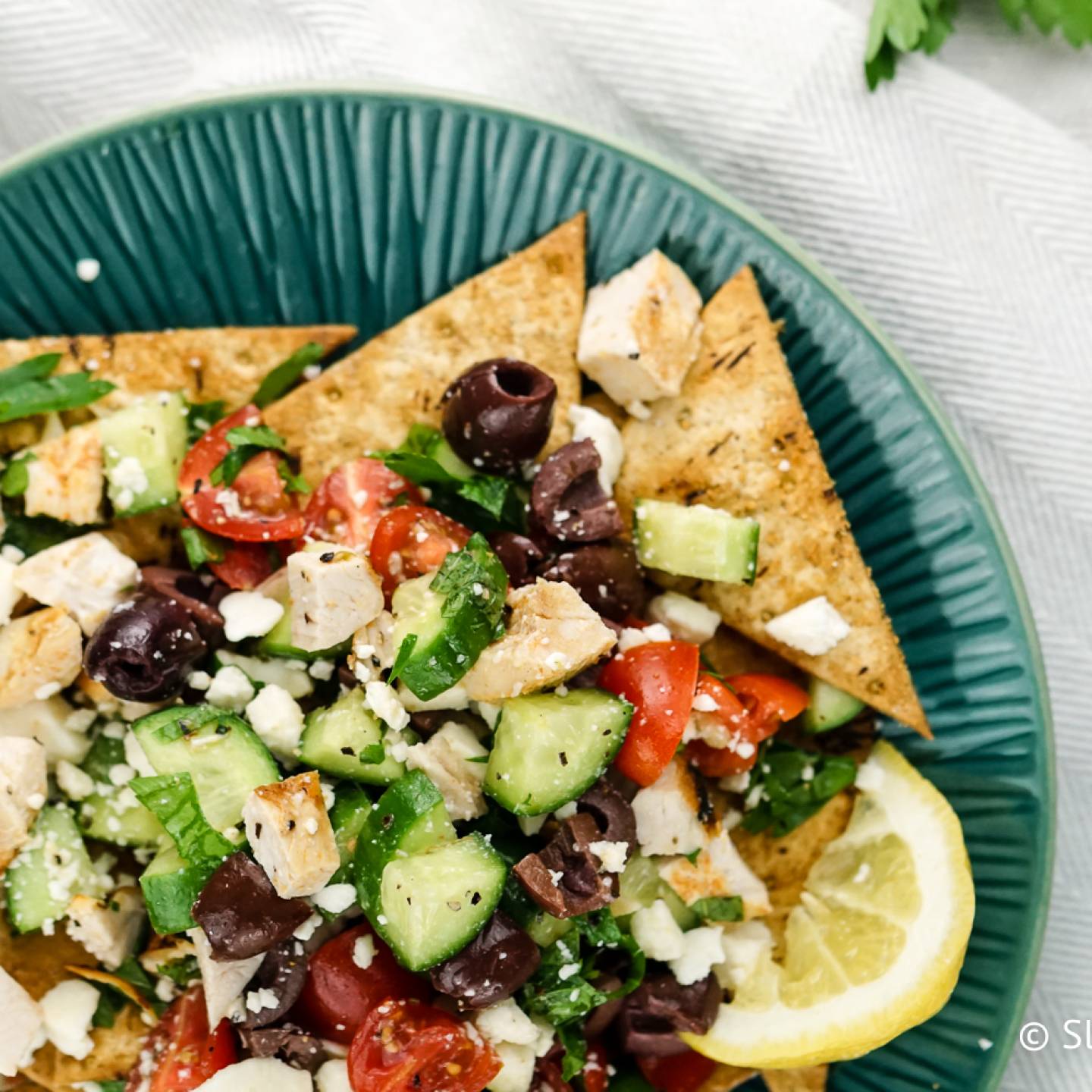 Greek nachos with chicken, cucumbers, tomatoes, red onions, feta cheese, and olives.