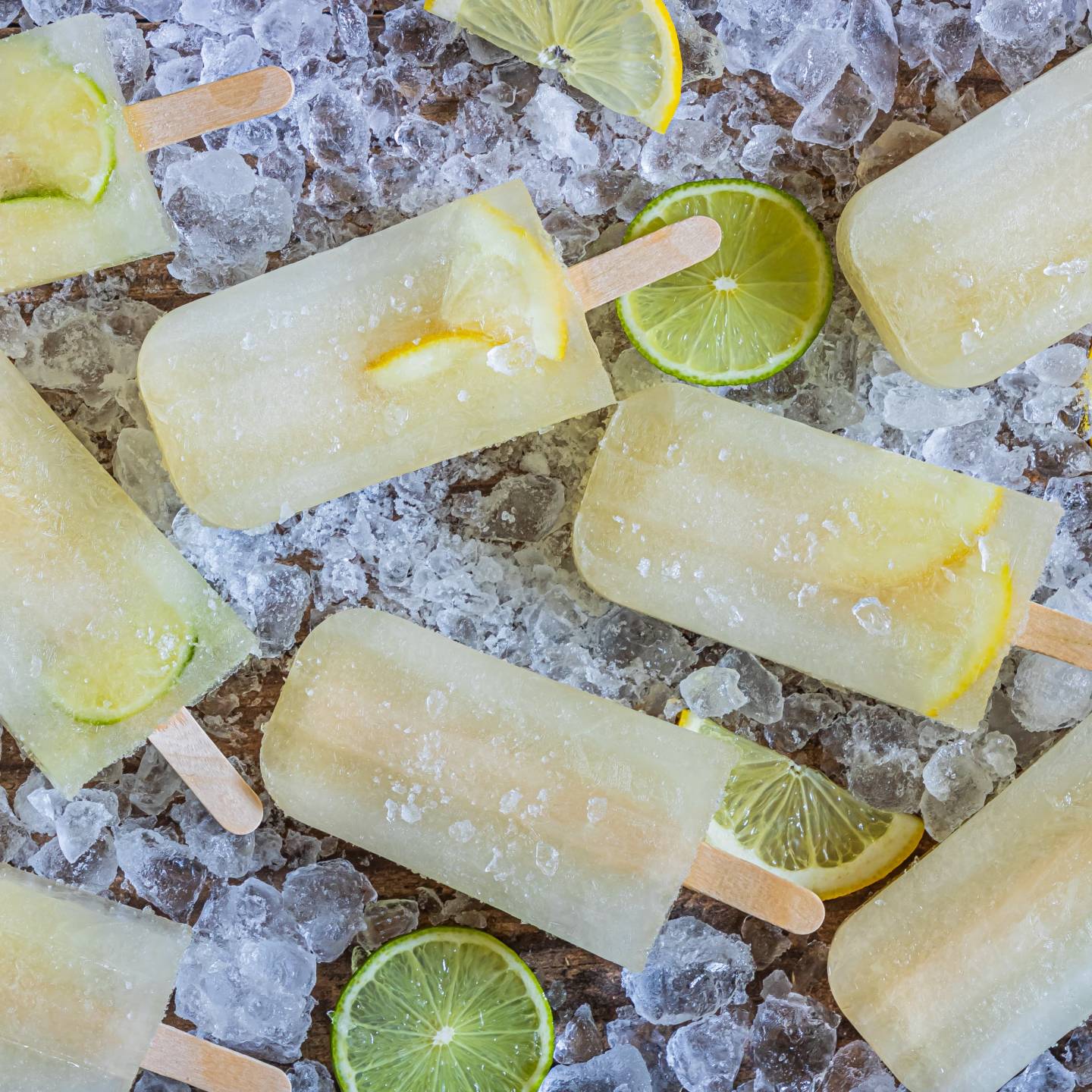 Lemon lime popsicles with fresh lemon and lime slices on a bed of ice.