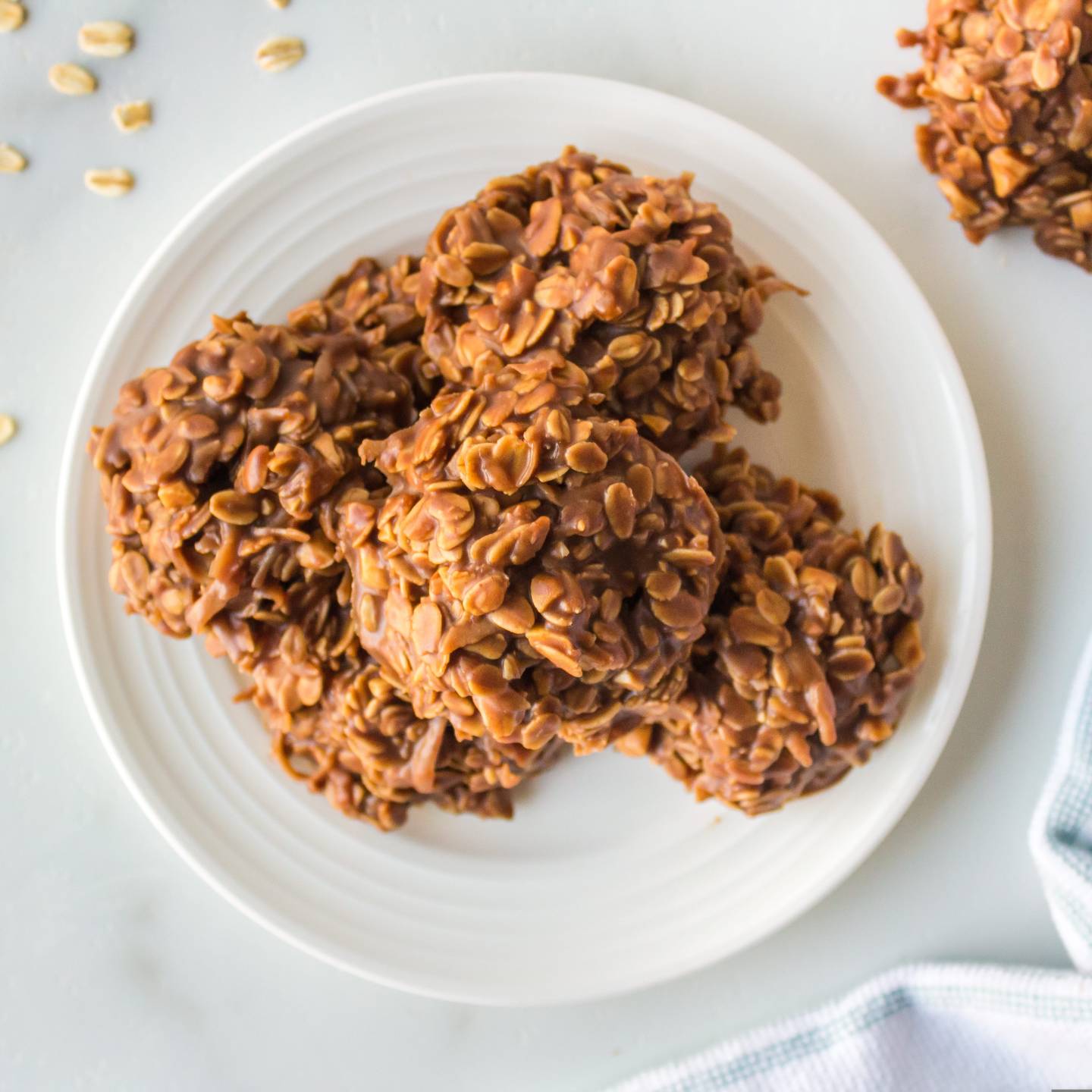 No bake peanut butter oatmeal cookies on a plate with loose oats on the side. 