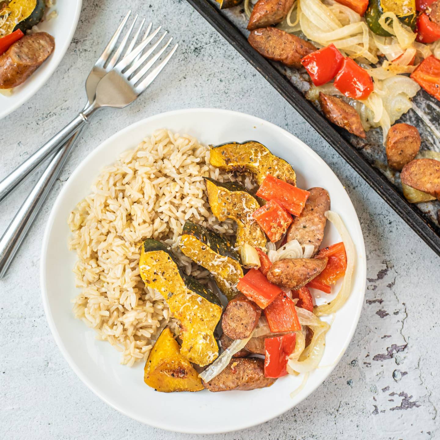 One pan sausage and acorn squash with bell peppers and onions on a plate with brown rice.